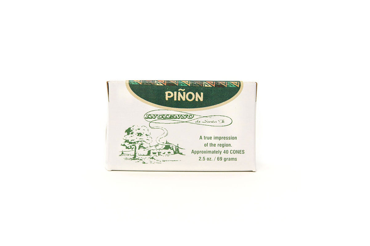 A box of Piñon incense featuring green illustrations of trees and a house with smoke rising, labeled “A true impression of the region. Approximately 40 cones, 2.5 oz. / 69 grams.”.