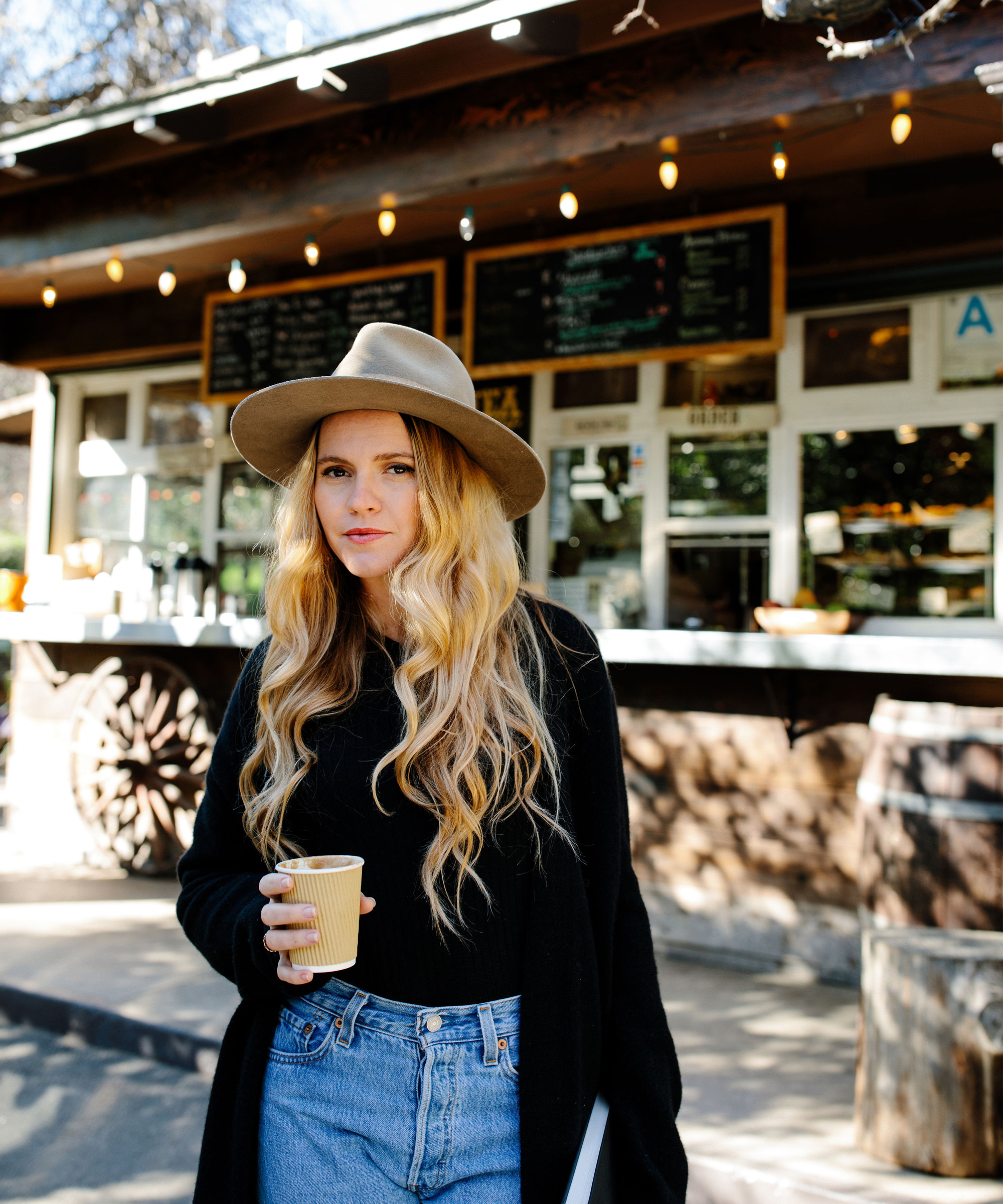 Lulu Brud portrait holding cup of coffee outside.