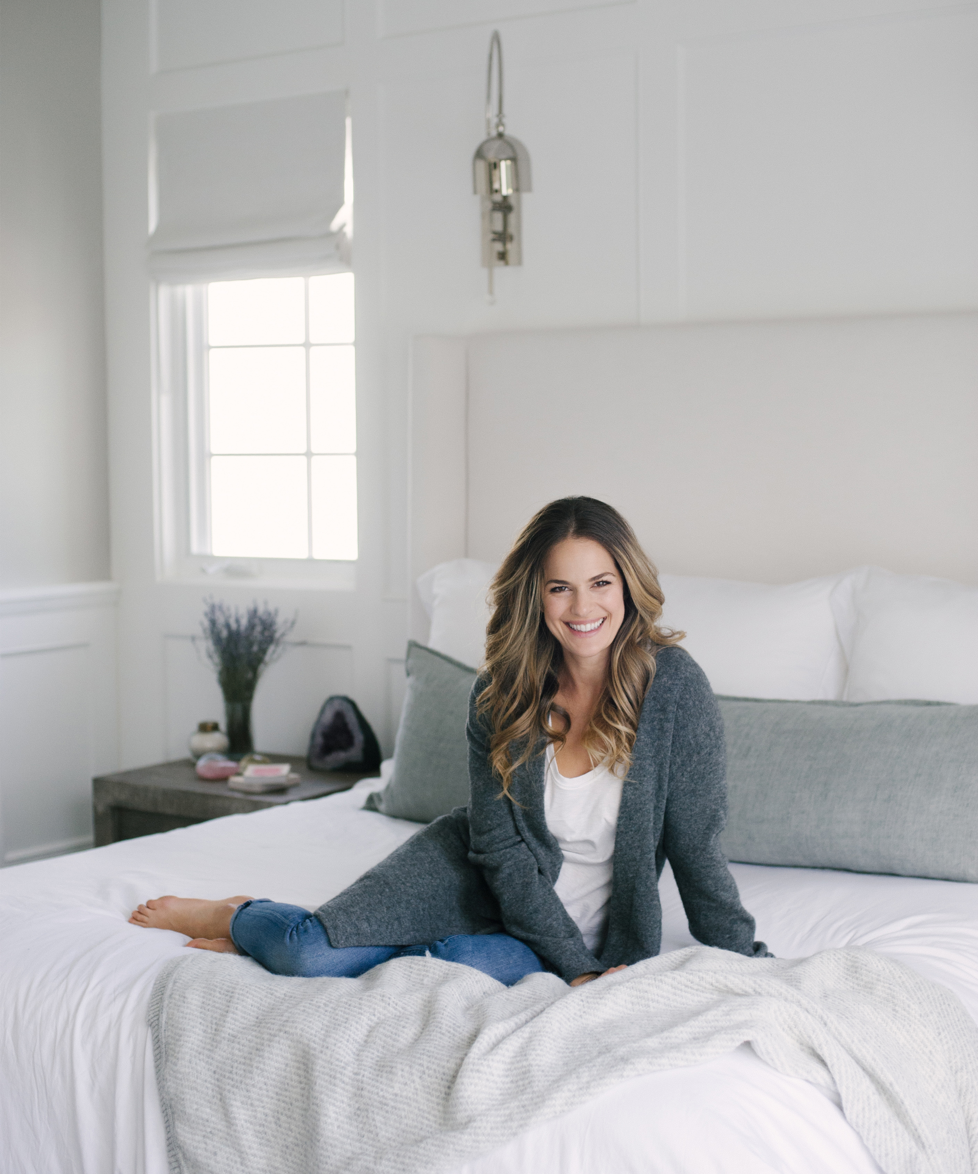 Zelana Montminy portrait sitting on bed in bedroom.