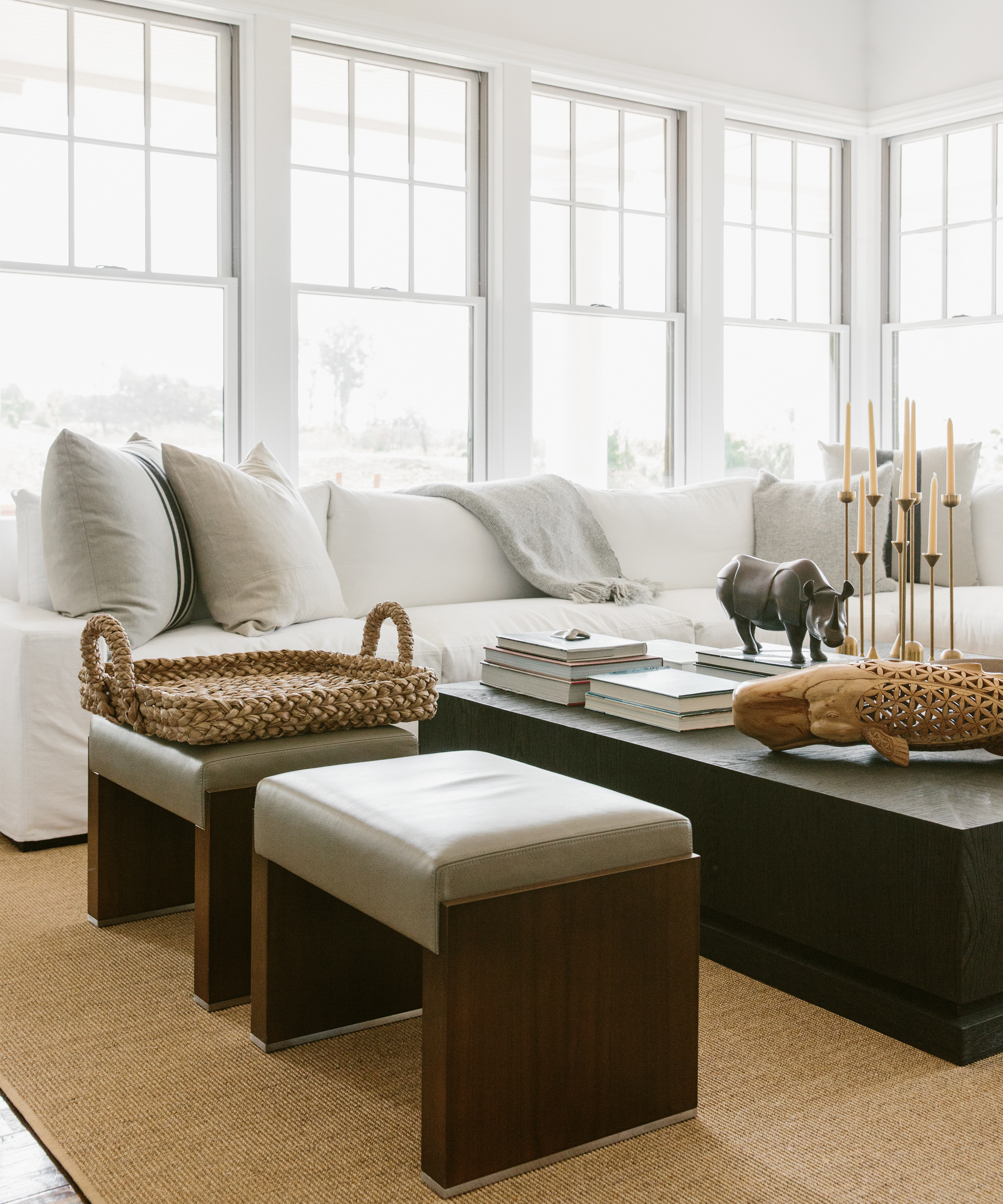 Living room with large white couch, large black coffee table, and two ottomans