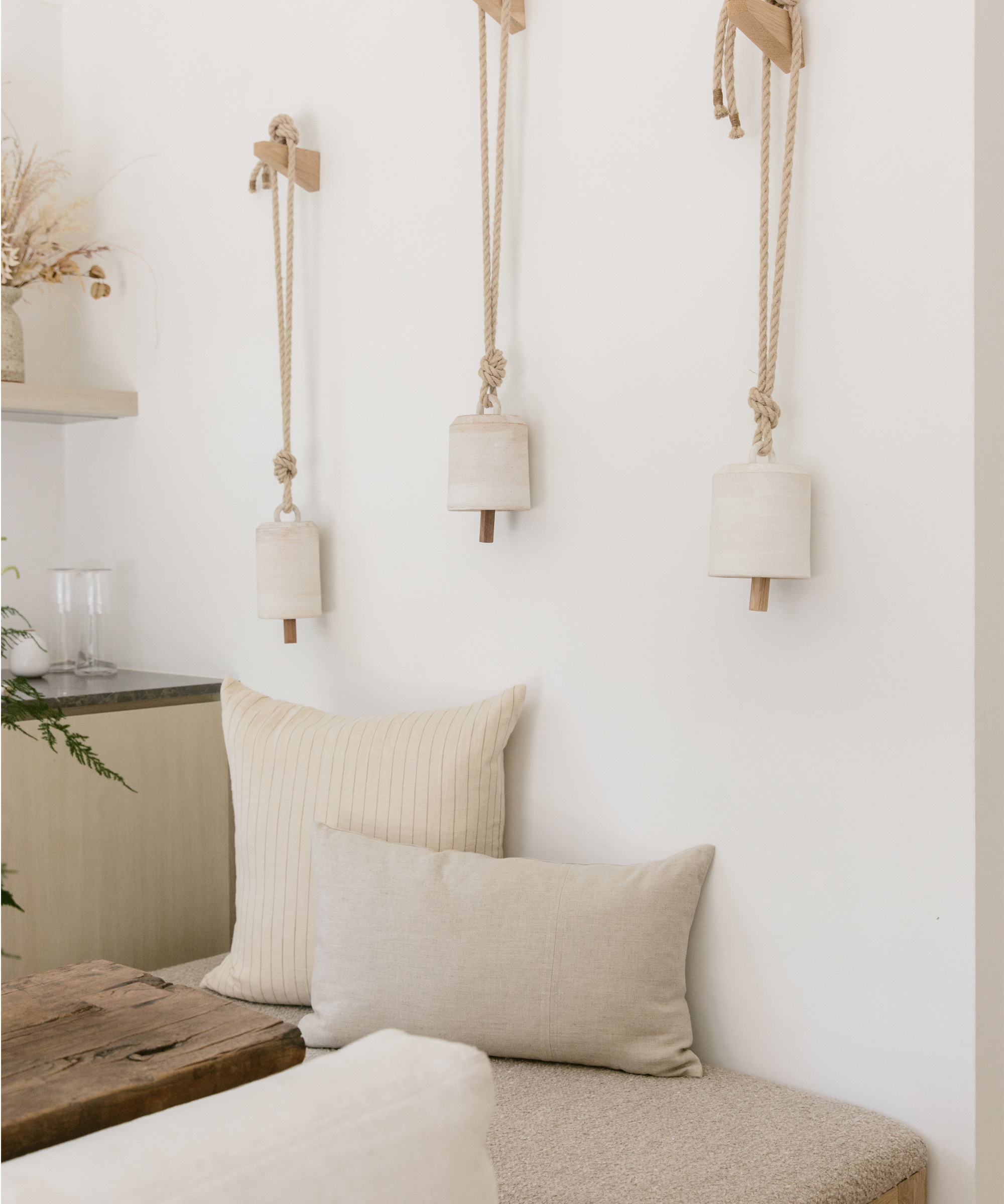 Tan colored cushion and pillows in front of a white wall.