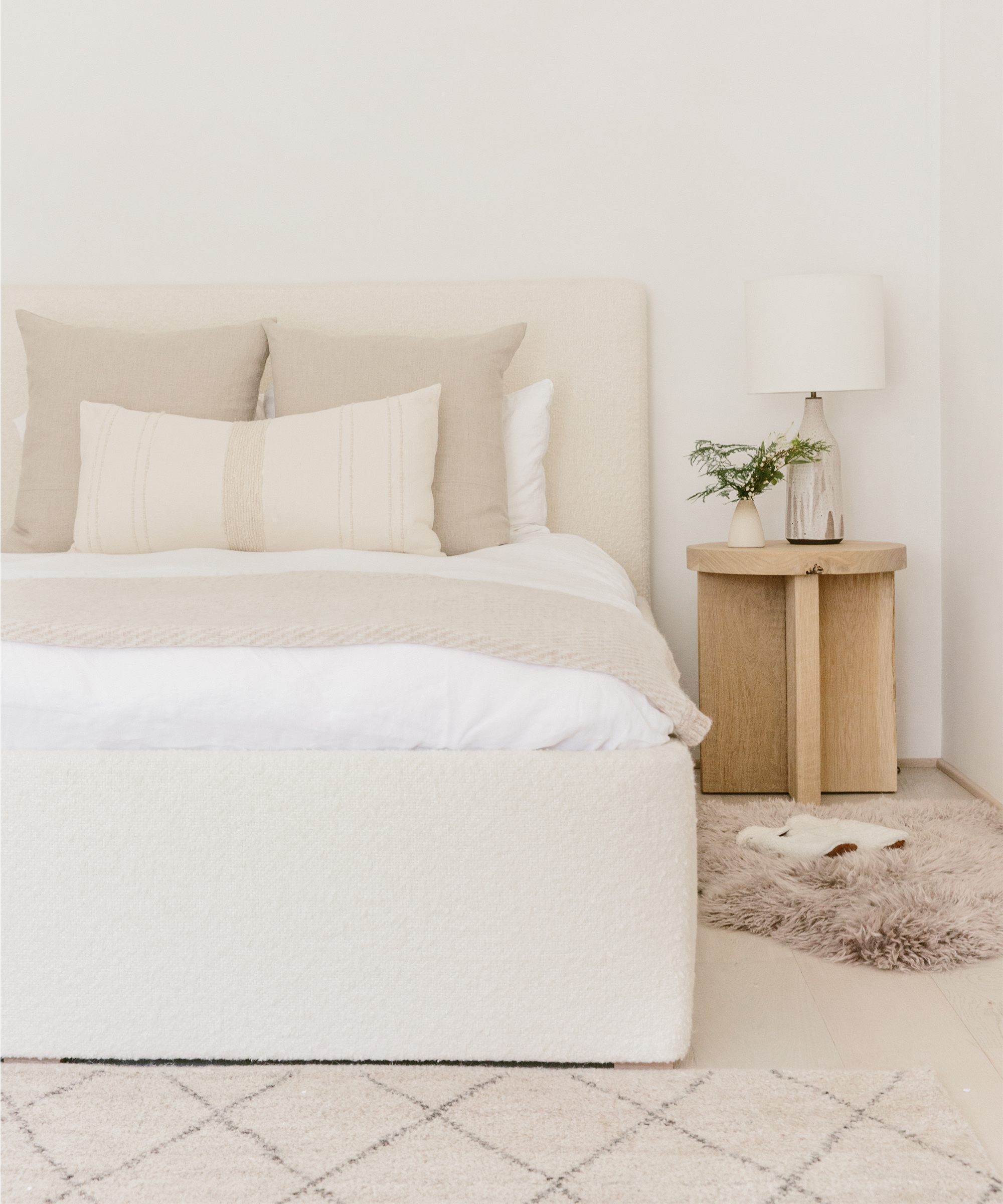 Interior of a bedroom with white bed, white rug, and white walls.
