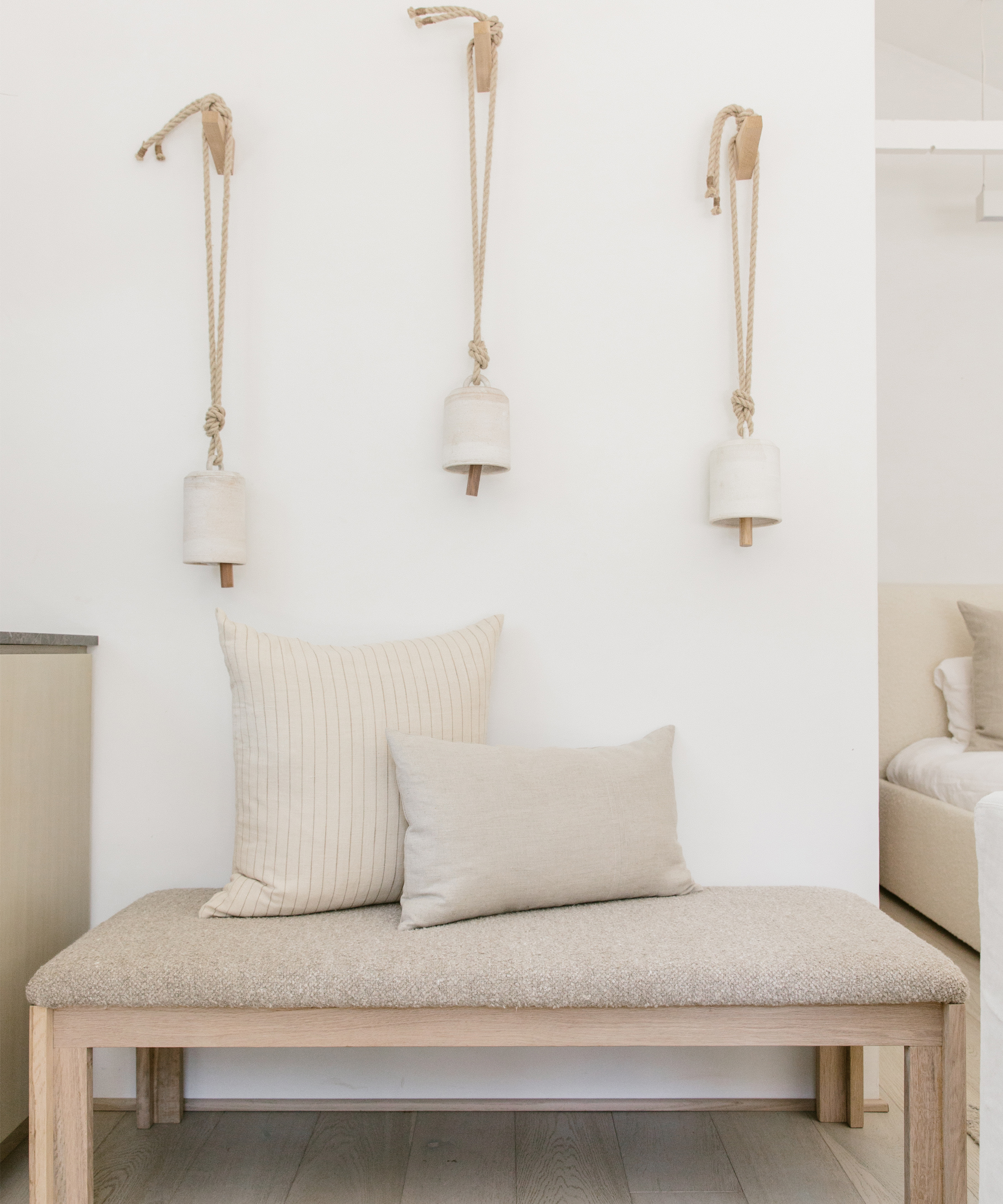 Wooden bench with cream colored cushion and pillows on it.
