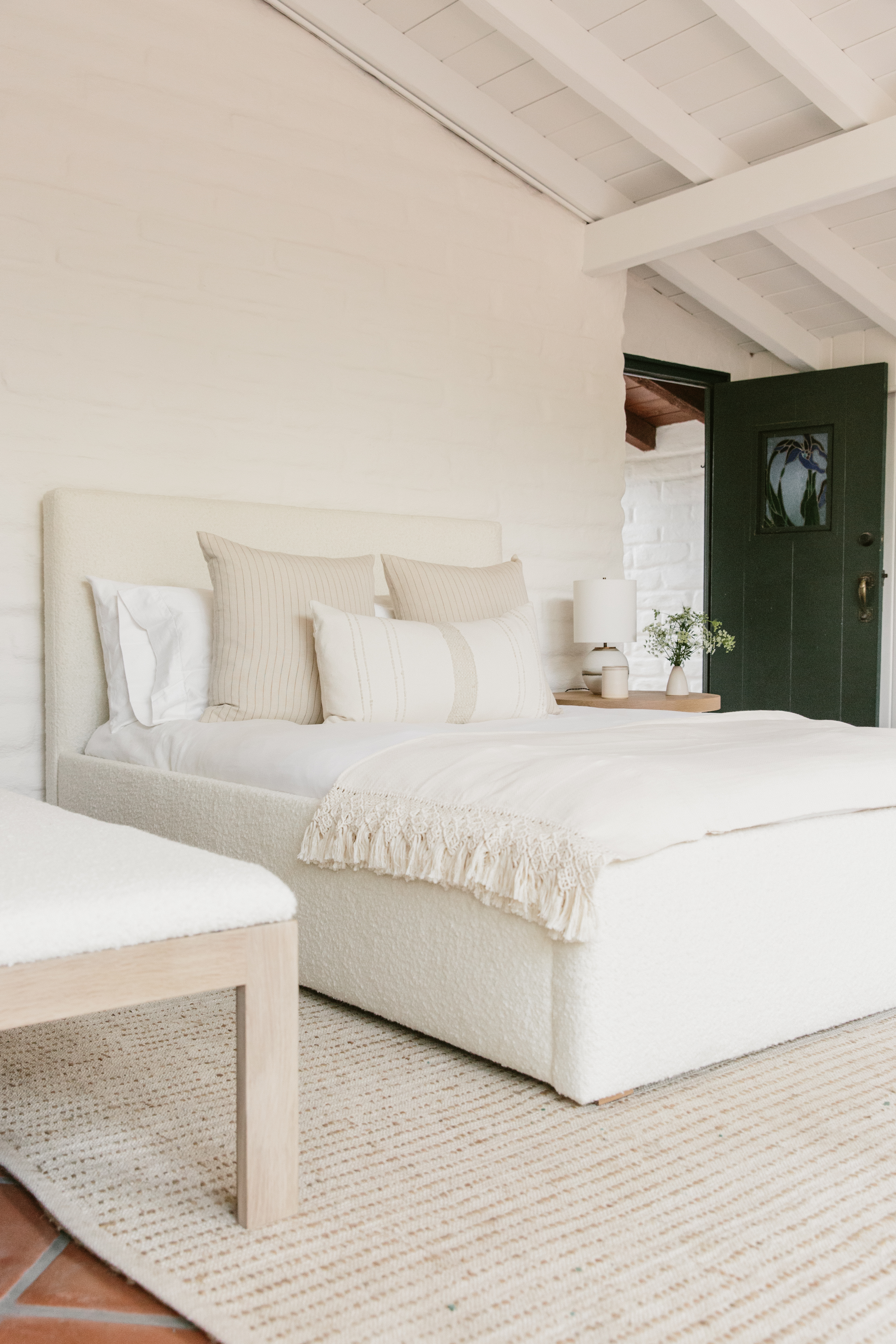 White bed, cream colored rug, and white walls.