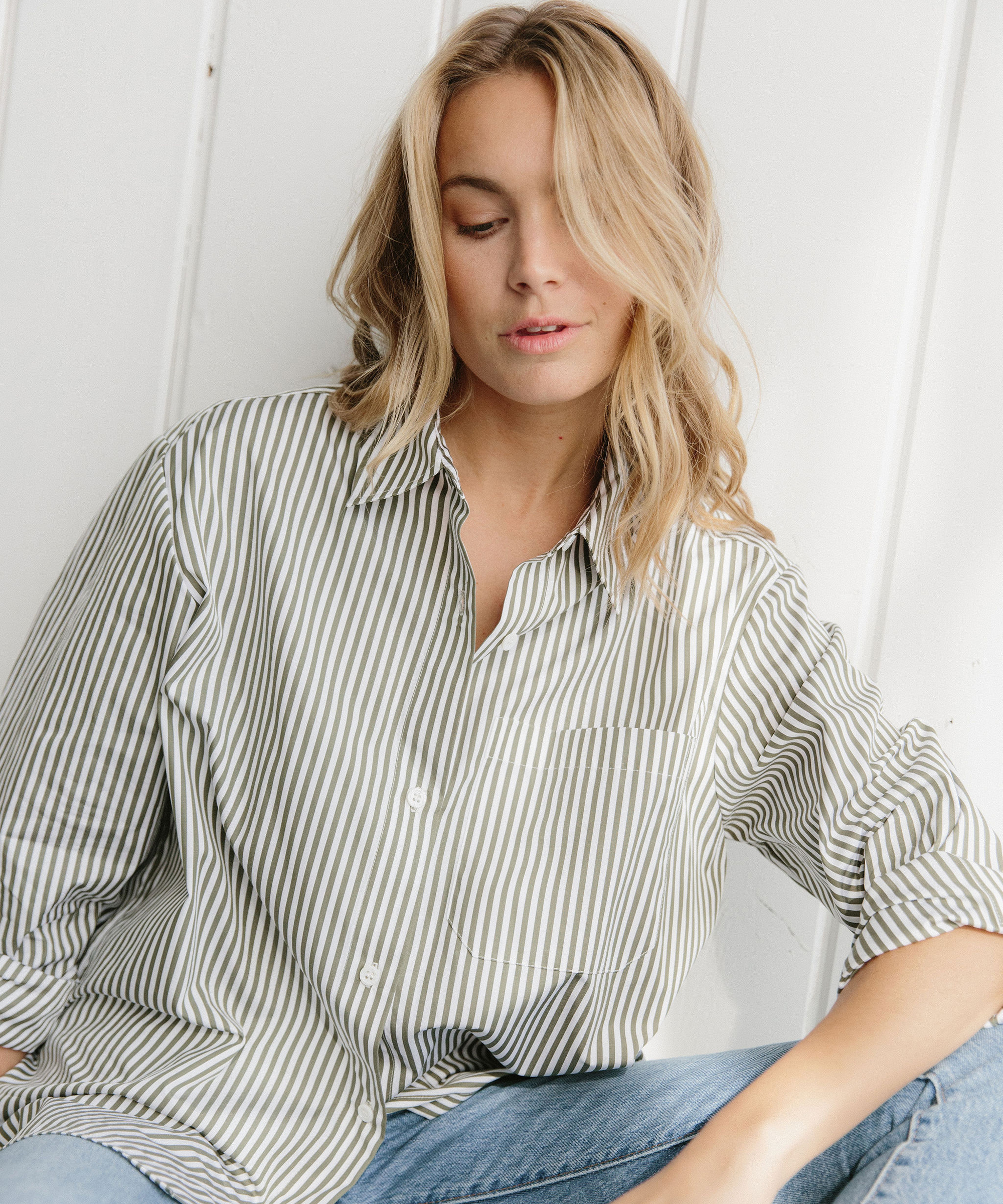 Woman wearing button up shirt and blue jeans.