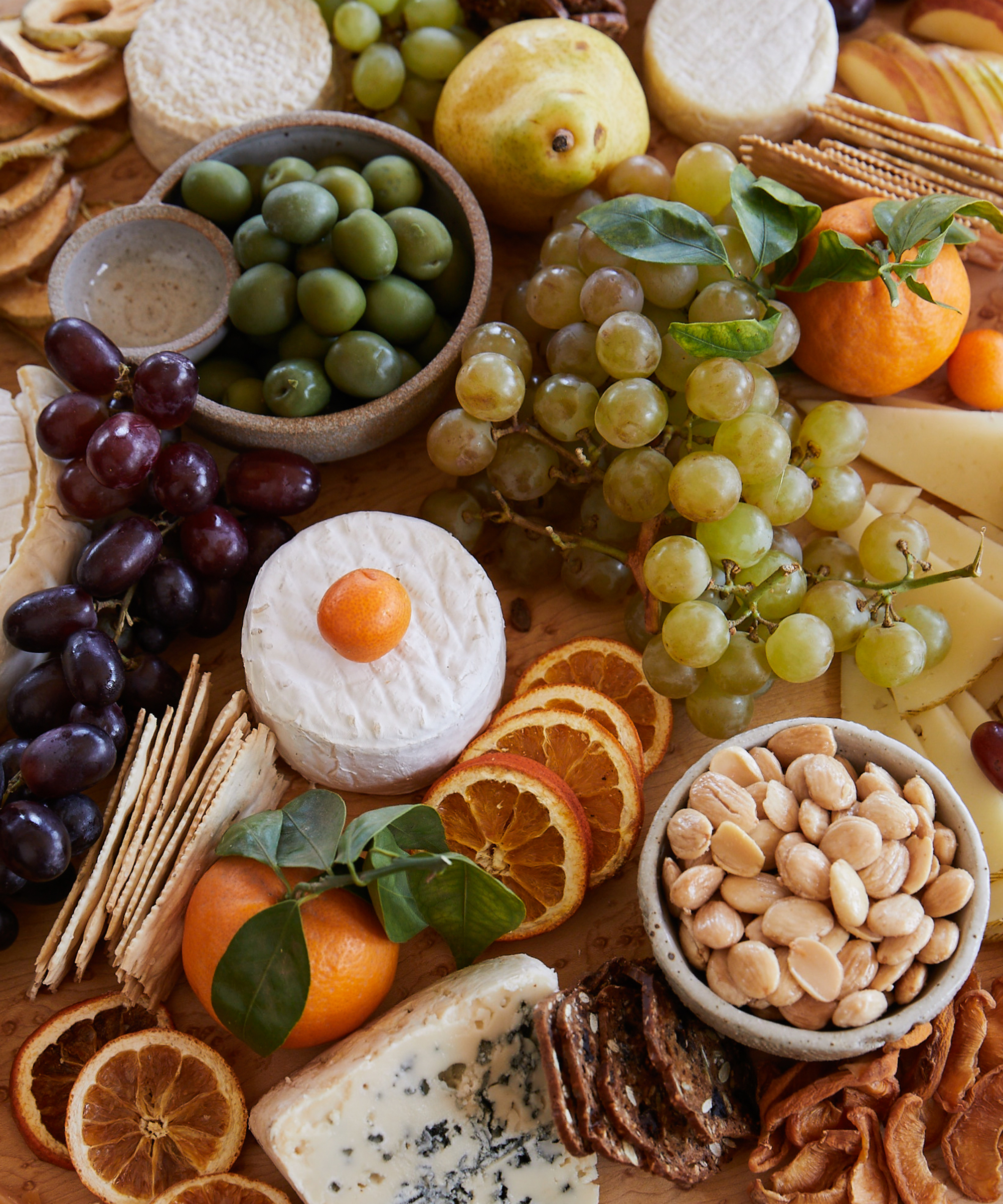 Close up photo of a cheeseboard with grapes, nuts, and an assortment of cheeses.