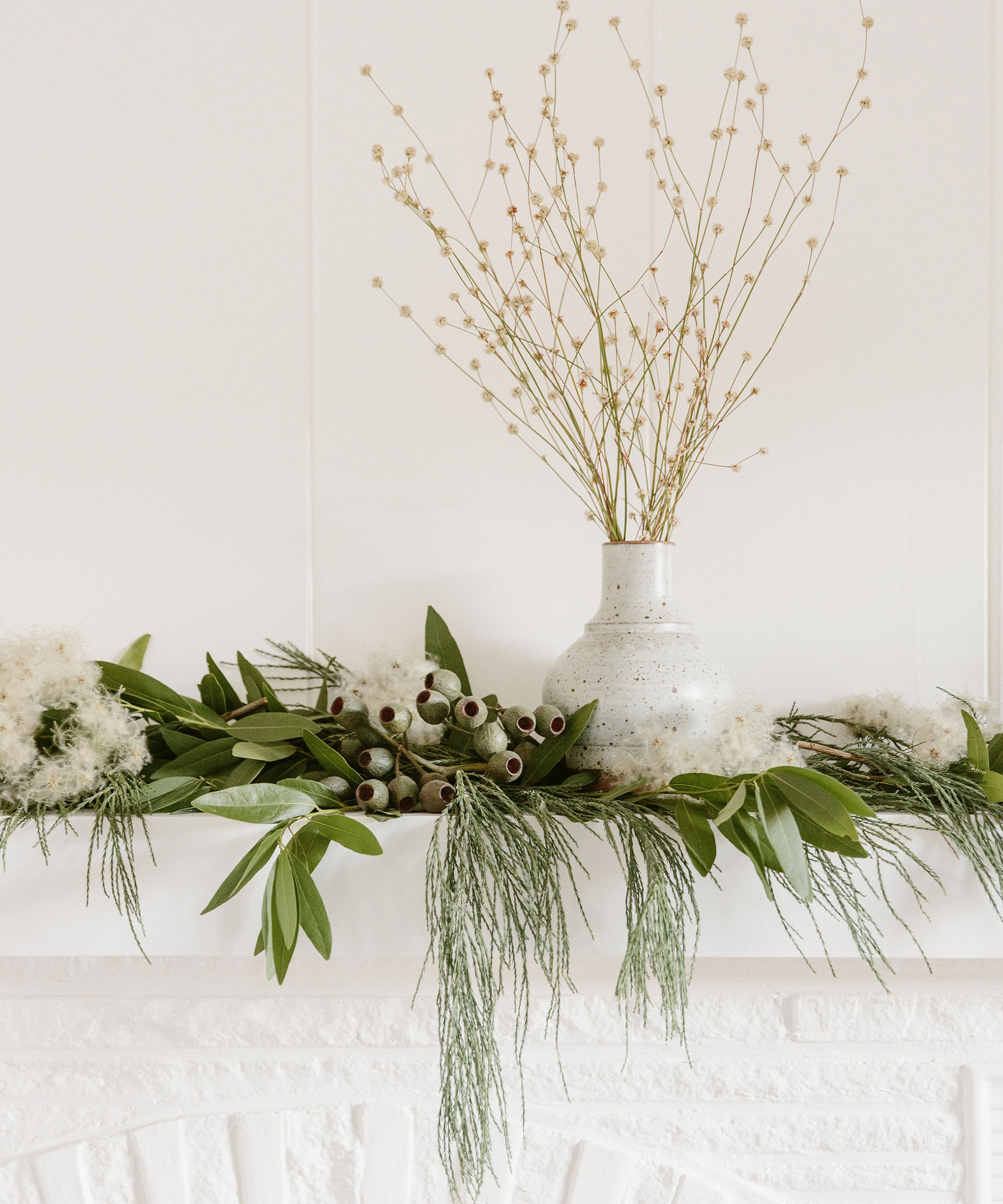 Festive holiday mantle decorated with branches and greenery.