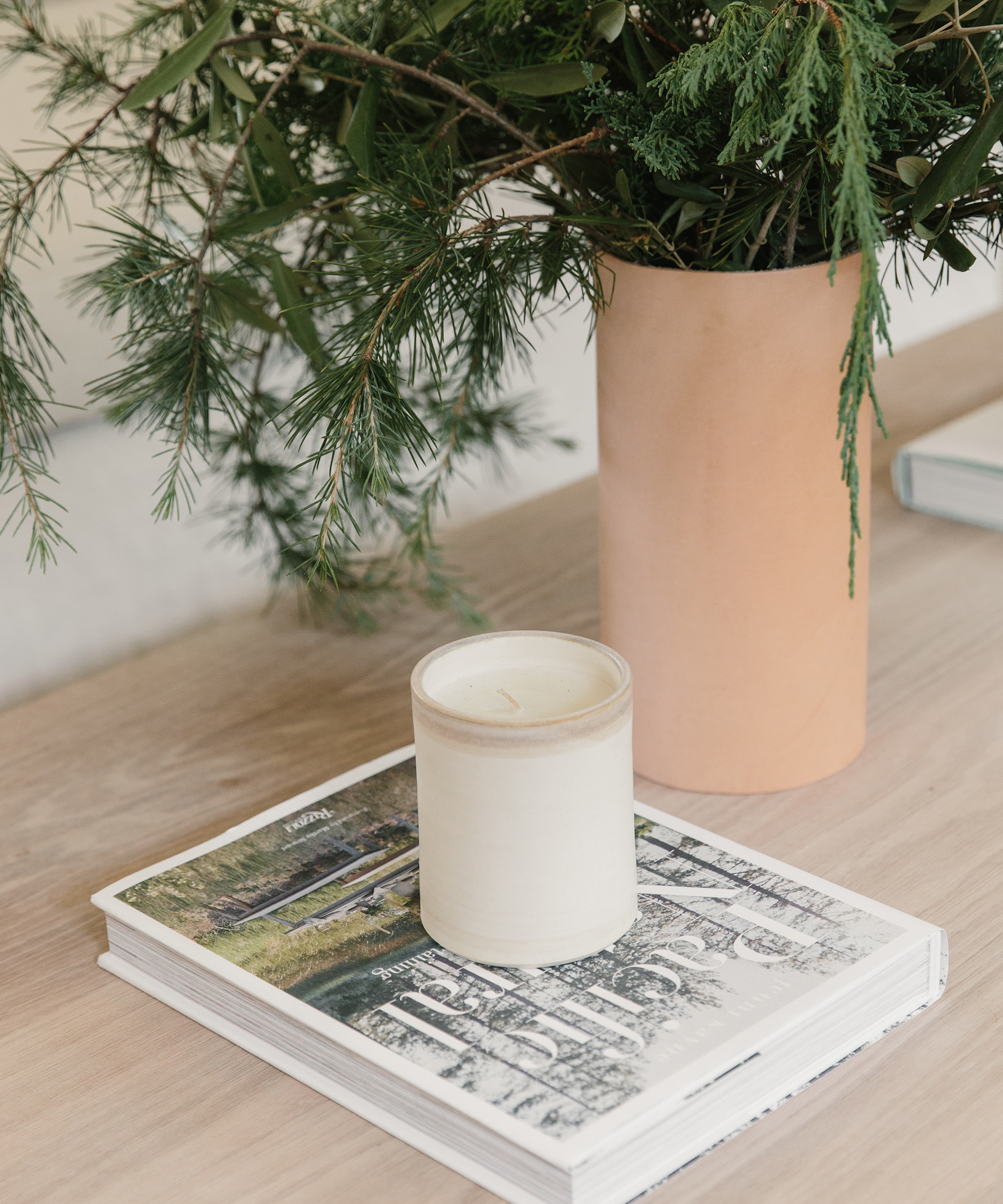 Pacific Natural, ceramic candle, and leather rivet vase on a tabletop.