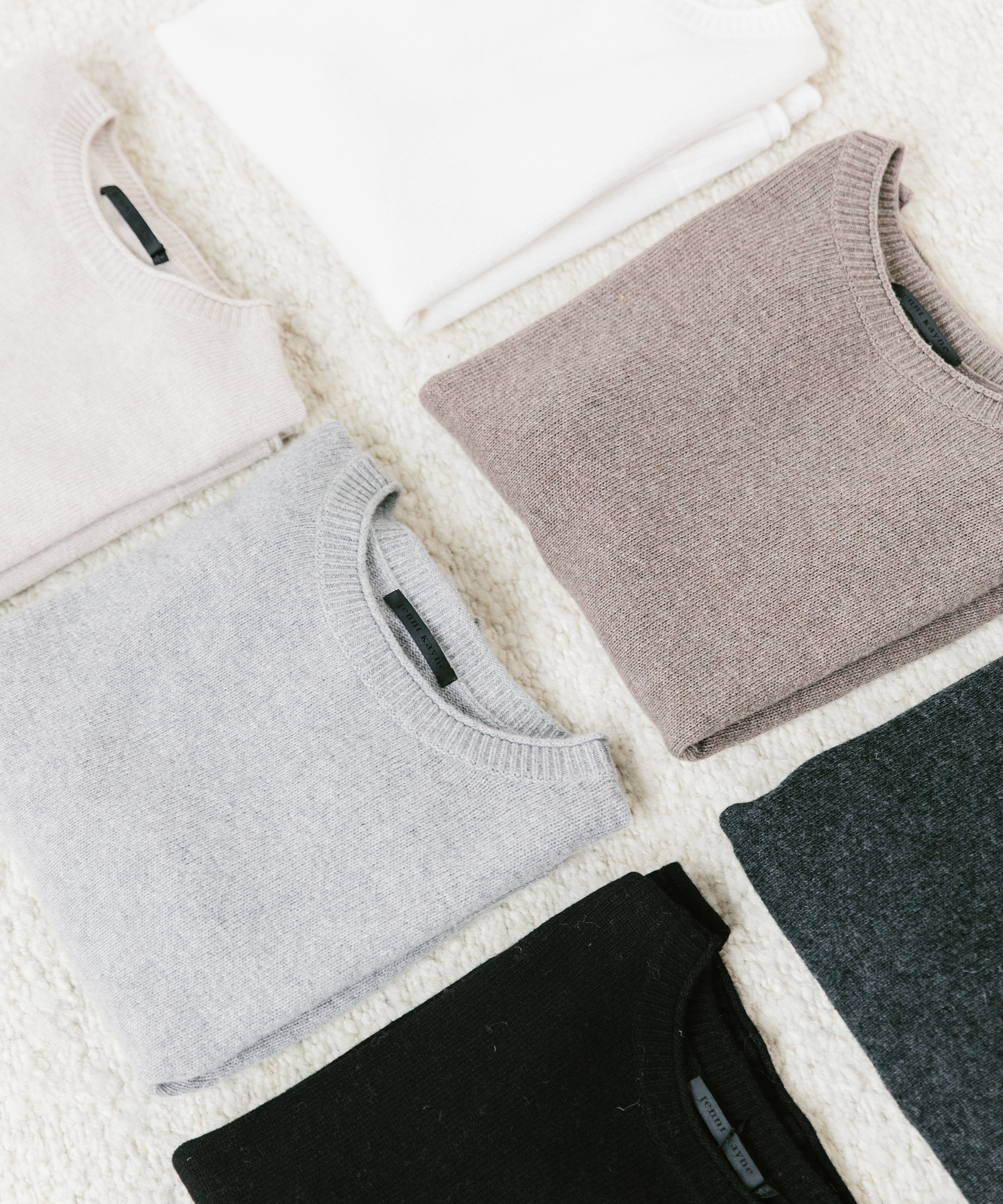 Jenni Kayne Everyday Sweaters folded on a carpet.