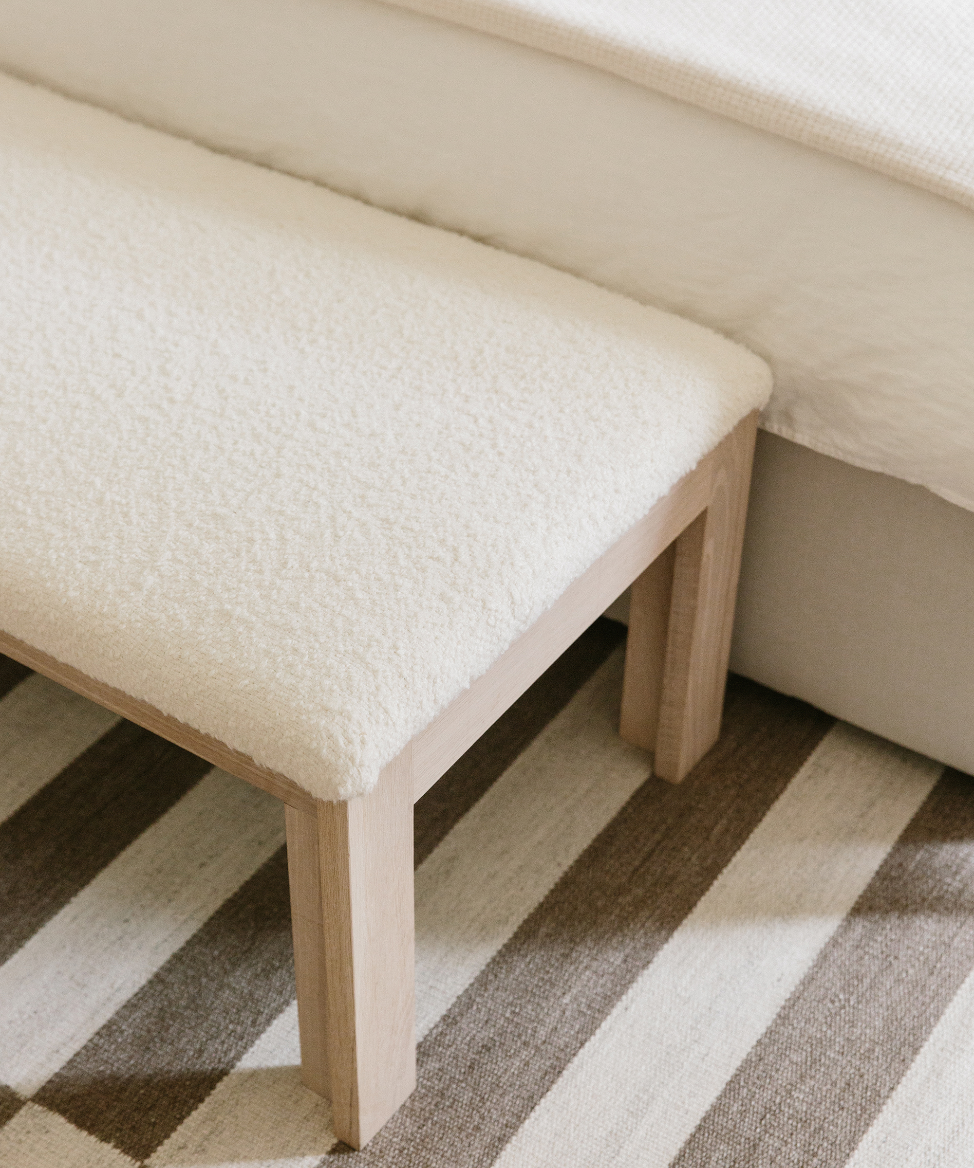 Jenni Kayne bungalow striped rug with upholstered bench on top.