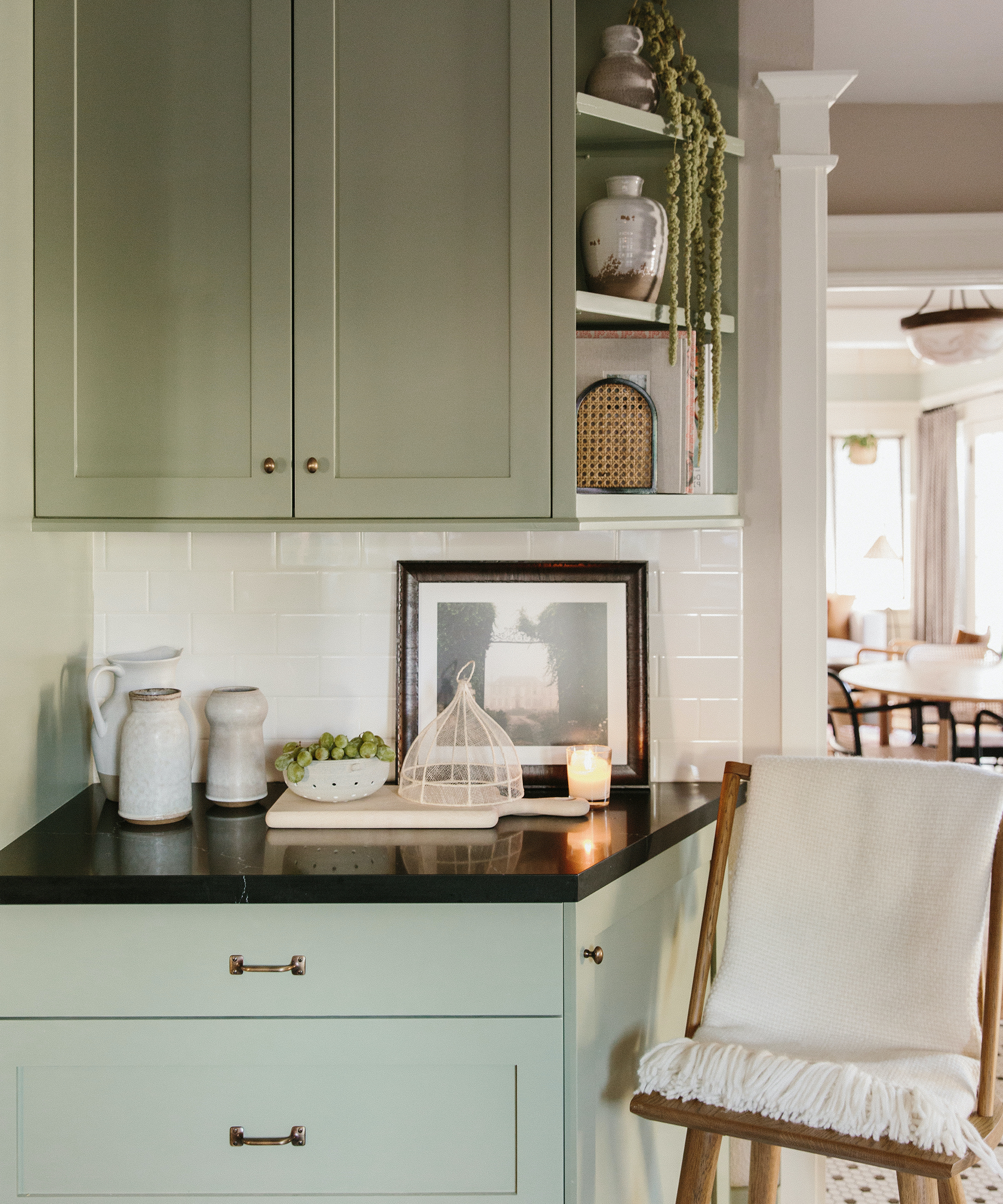 Jacey Duprie's kitchen with cabinets and black countertops and a chair with a jenni kayne alpaca throw in ivory.