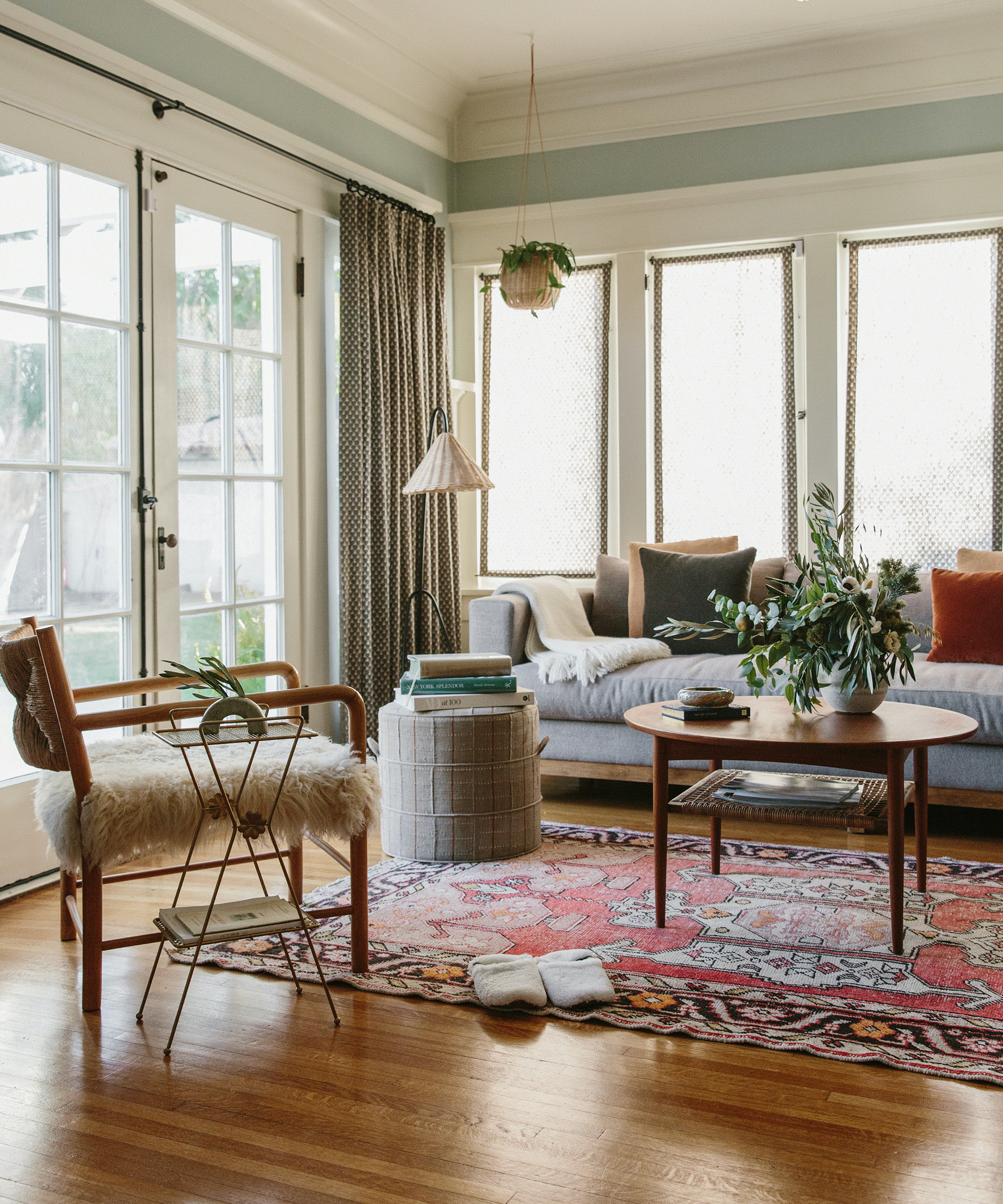 Jacey Duprie's living room with an assortment of contemporary and vintage furniture, a hanging plant, and jenni kayne slippers.