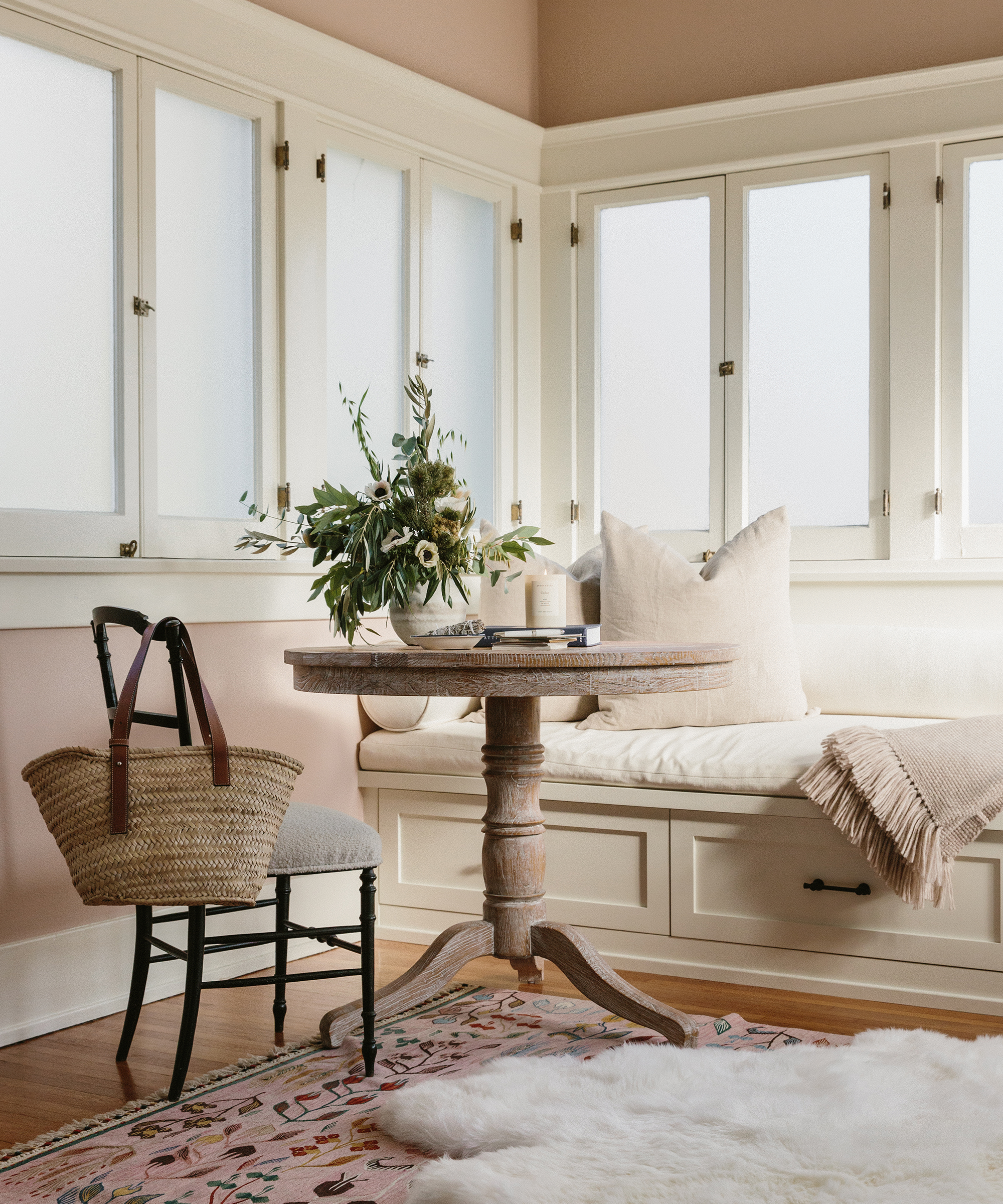 Jacey Duprie's living room with day bench, small table, and chair with a patterned rug.