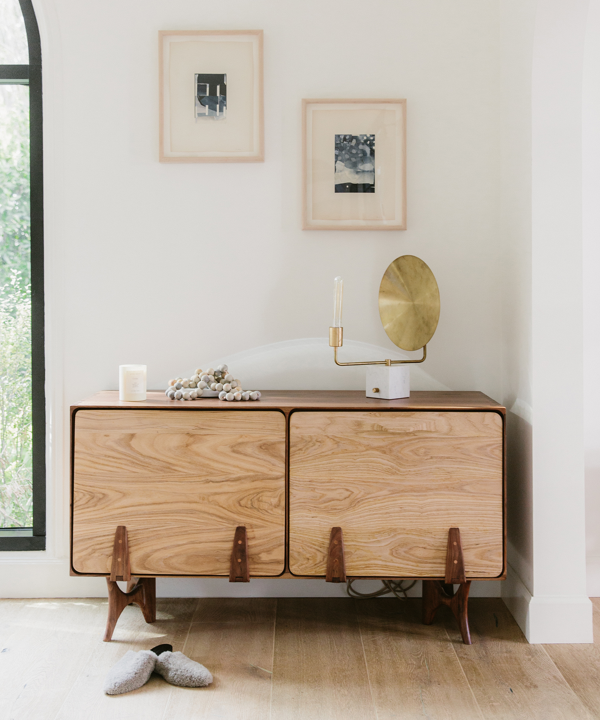 Camilla Marcus' home with wooden credenza and a pair of jenni kayne shearling mules in front of it.