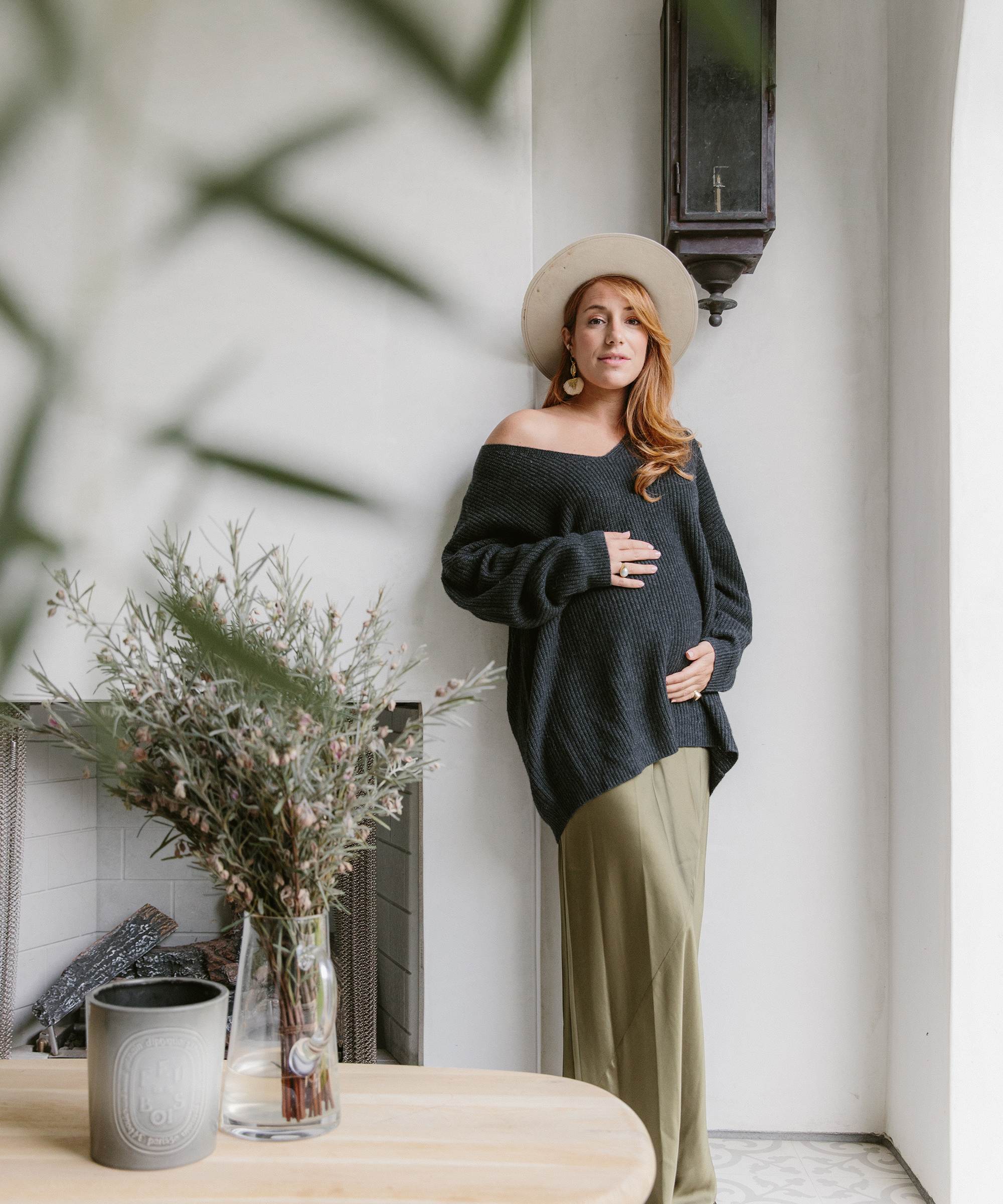 Camilla Marcus standing outside inher backyard wearing a jenni kayne cabin sweater and green dress.