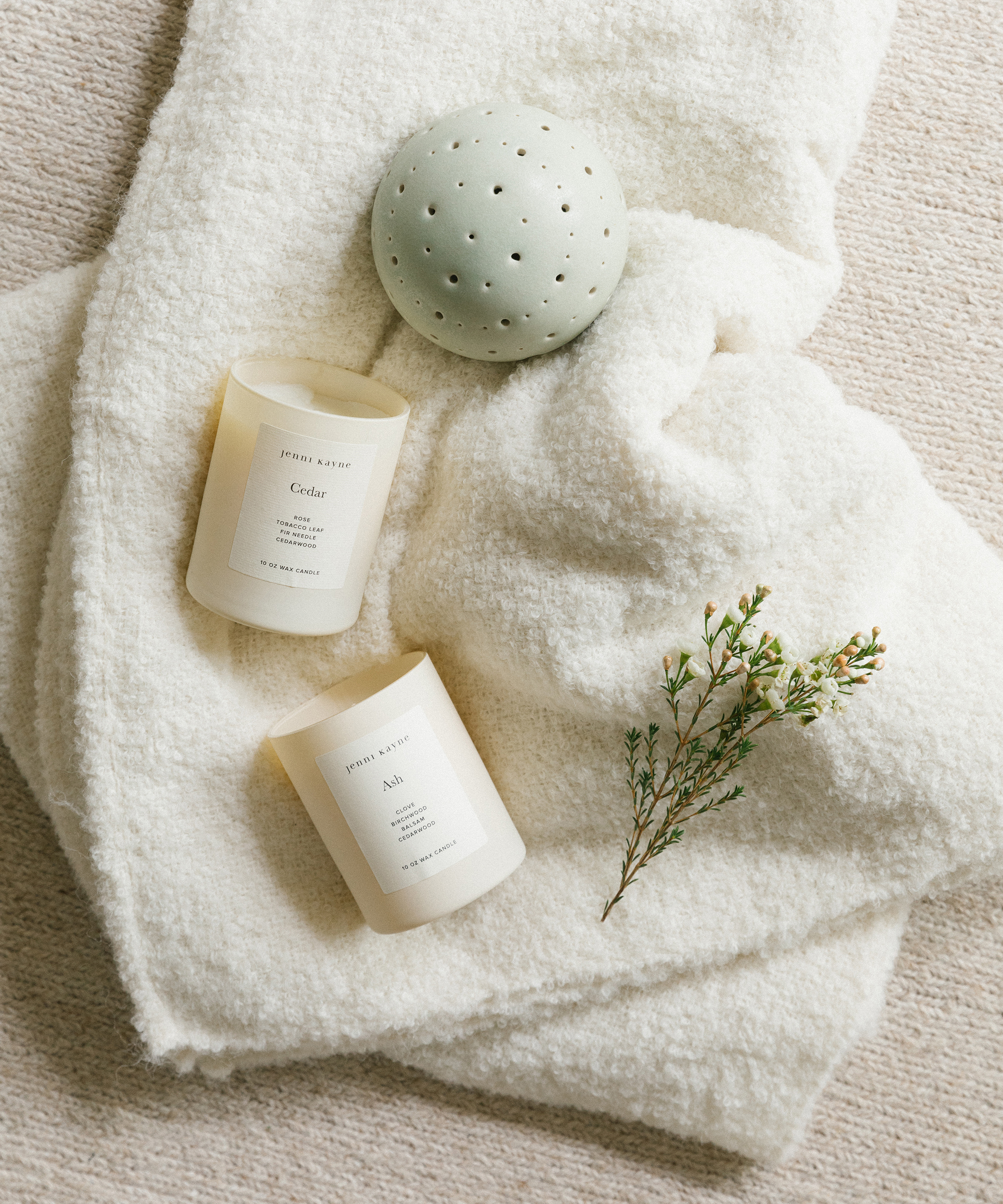 Jenni kayne aspen boucle throw with two candles and a mist musk diffuser sitting on top of it.