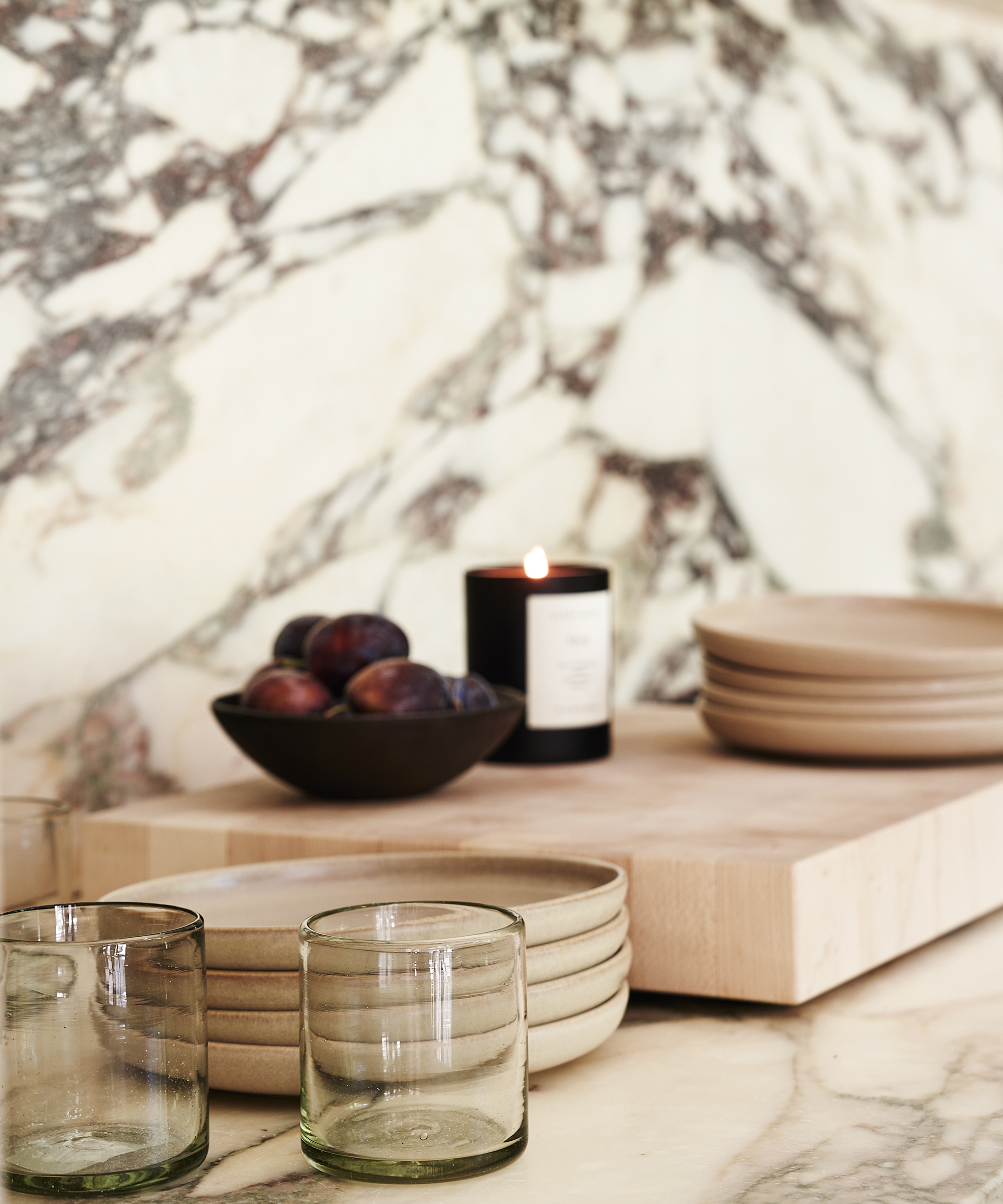 marble kitchen countertop with burning candle and a cutting board and clear glassware
