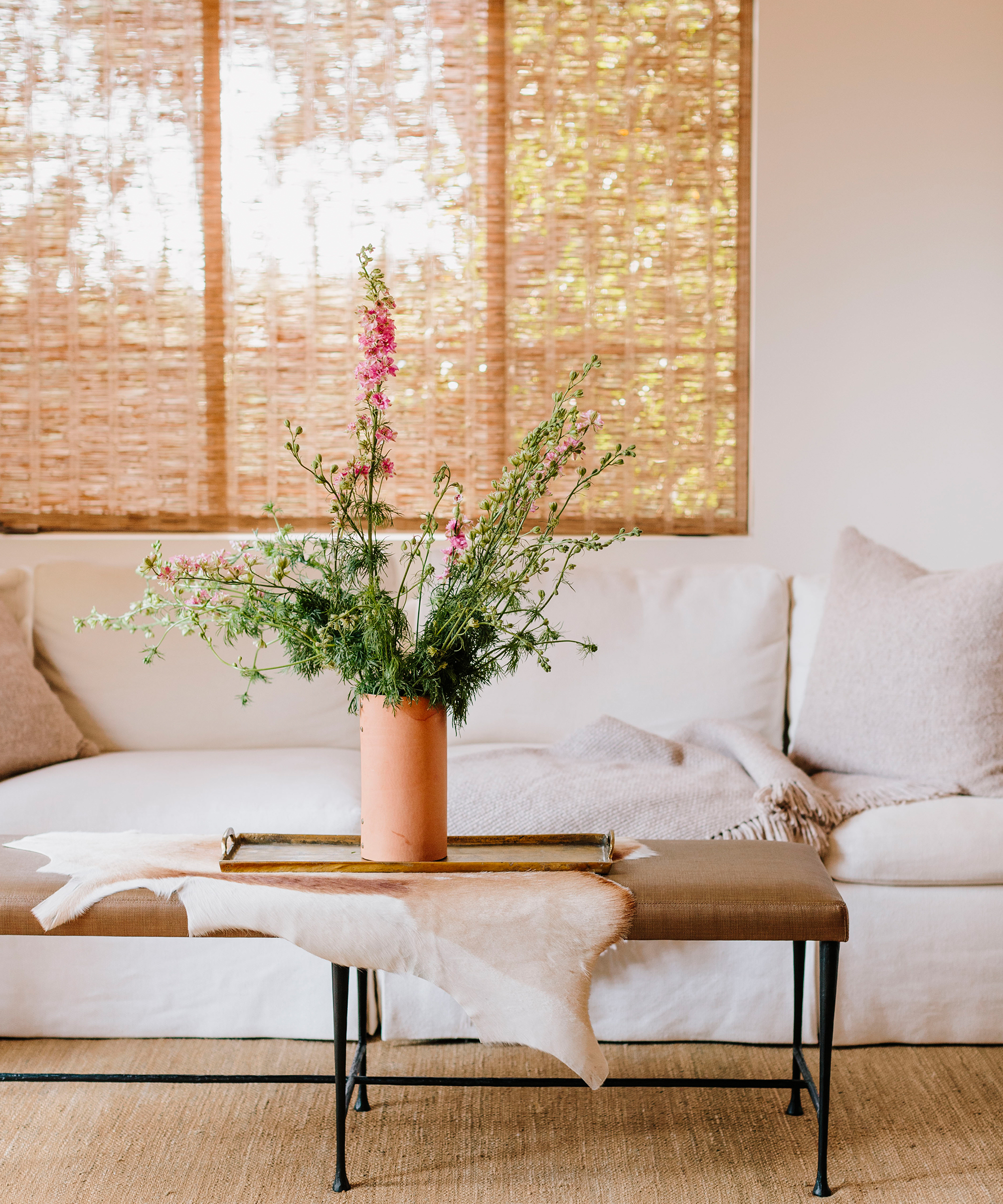Brit Hines' guest room with ivory linen sofa, jenni kayne alpaca pillows and throws, and jenni kayne leather rivet vase with florals inside.