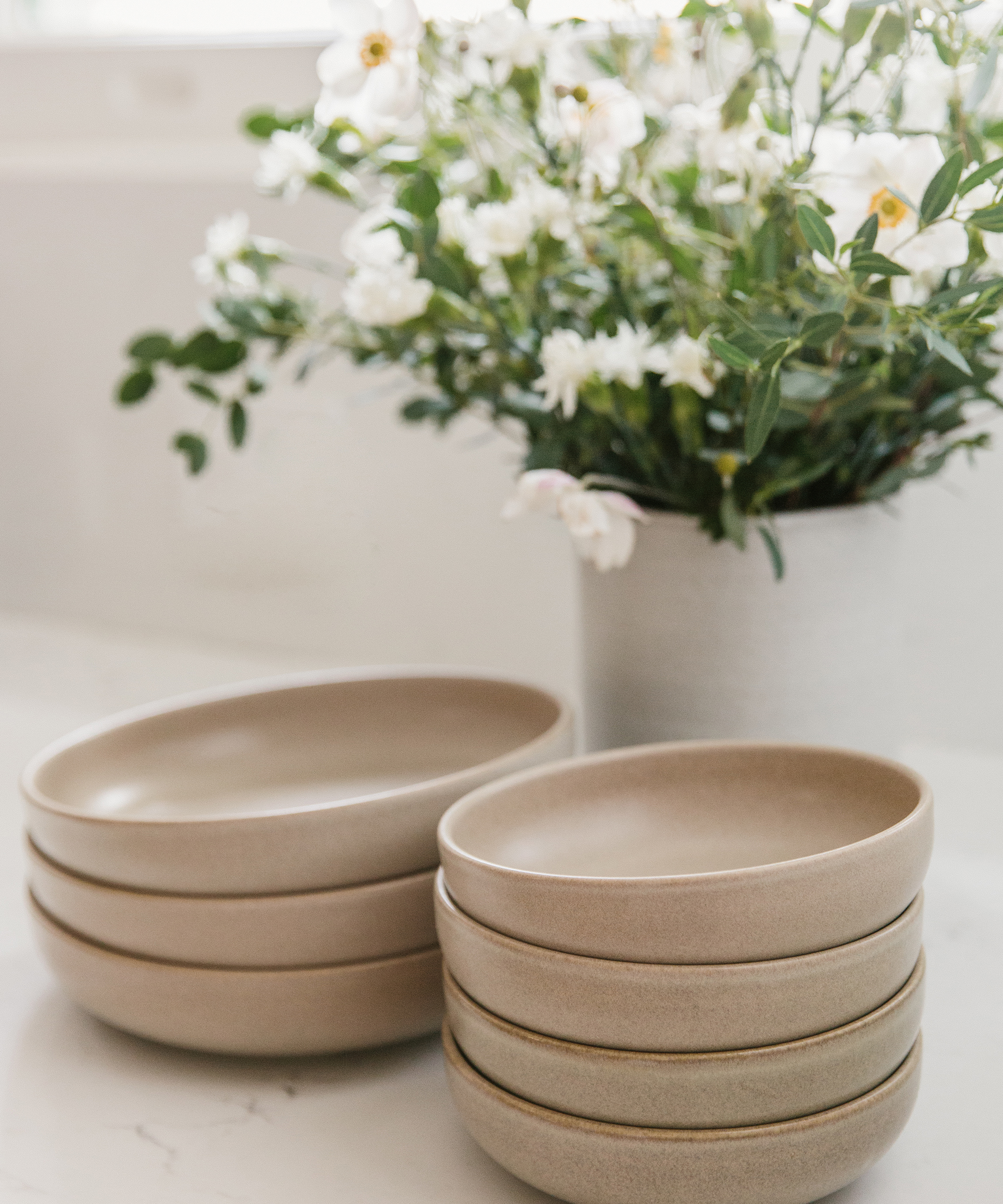 Jenni Kayne Pacific Dinnerware bowls sitting on a countertop next to Tracie Hervy vase.