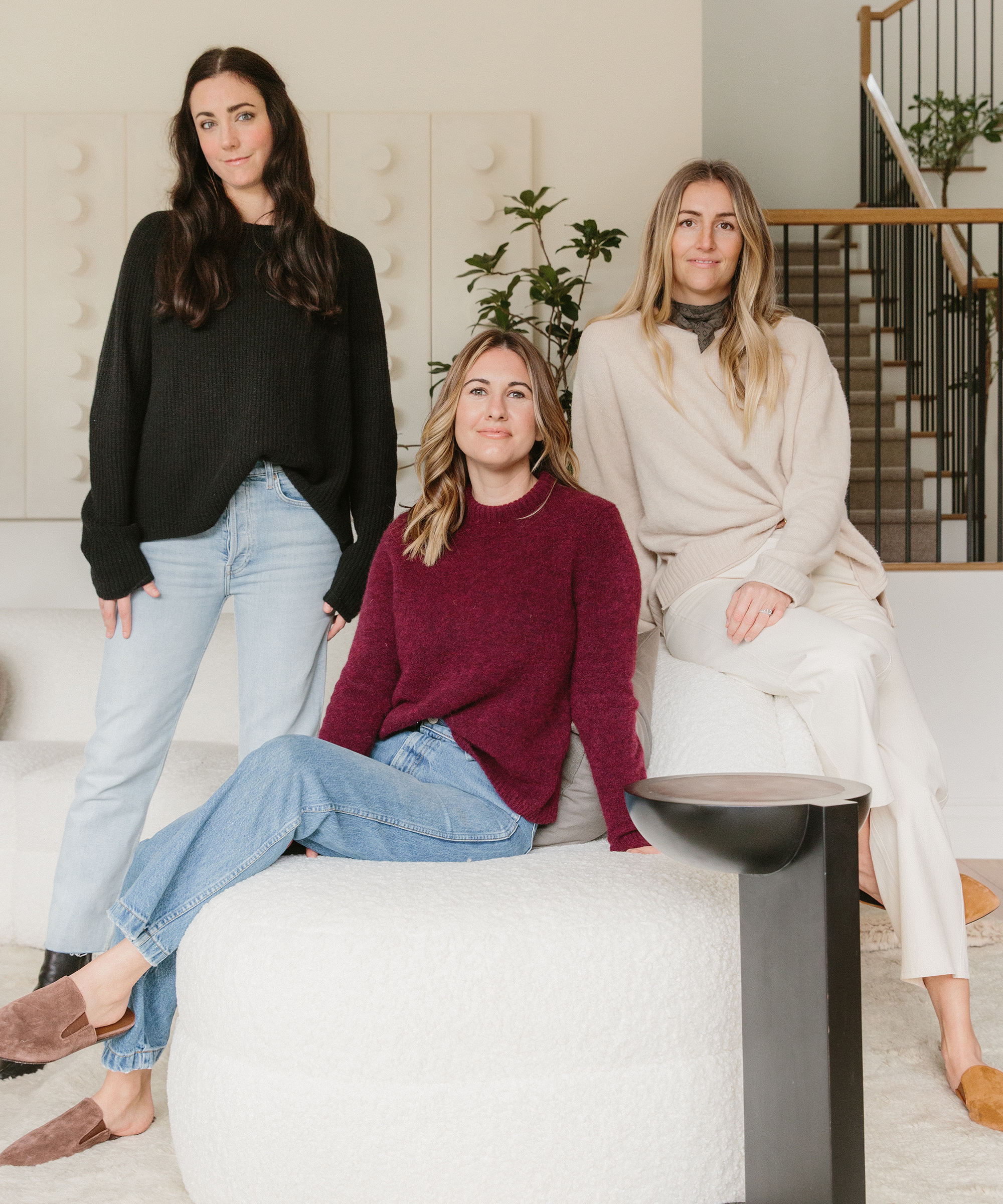 Kelli, Jenna, and Lauren of Transition State sitting in the living room wearing Jenni Kayne suede mules, sweaters, and wide leg cropped pant.