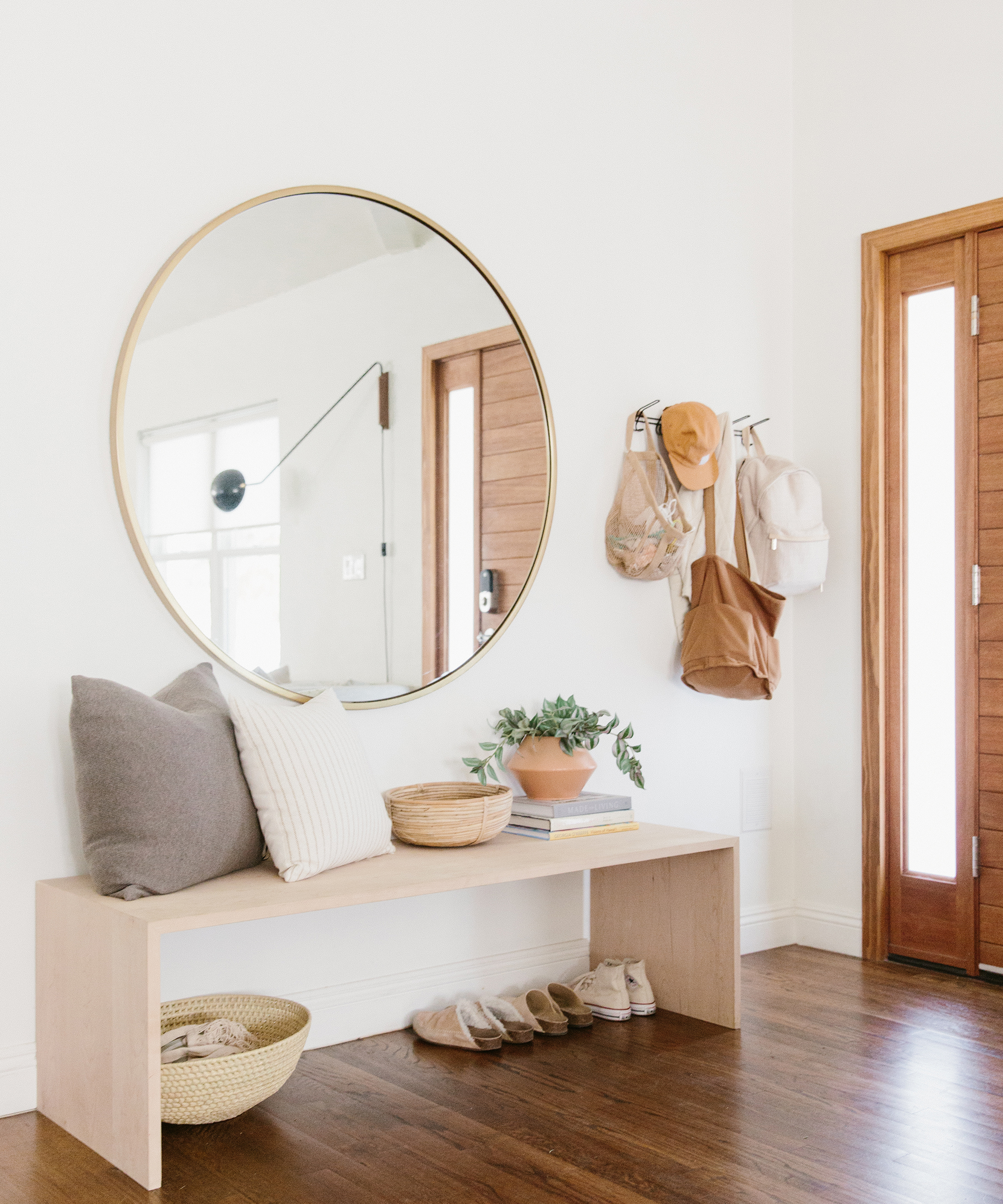Molly Madfis of Almost Makes Perfect's entryway with a round mirror, jenni kayne pillows, jenni kayne mocs, and bags.