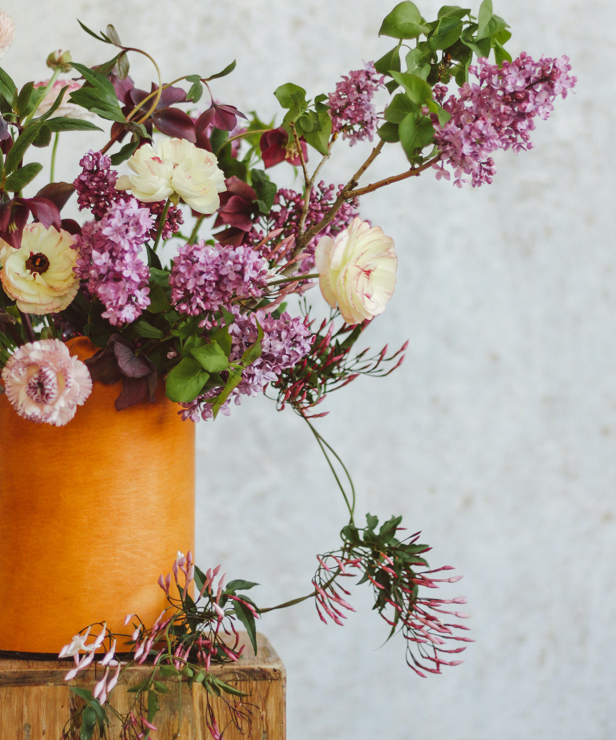 Floral arrangement by Moon Canyon with spring flowers in a leather wrapped vase.