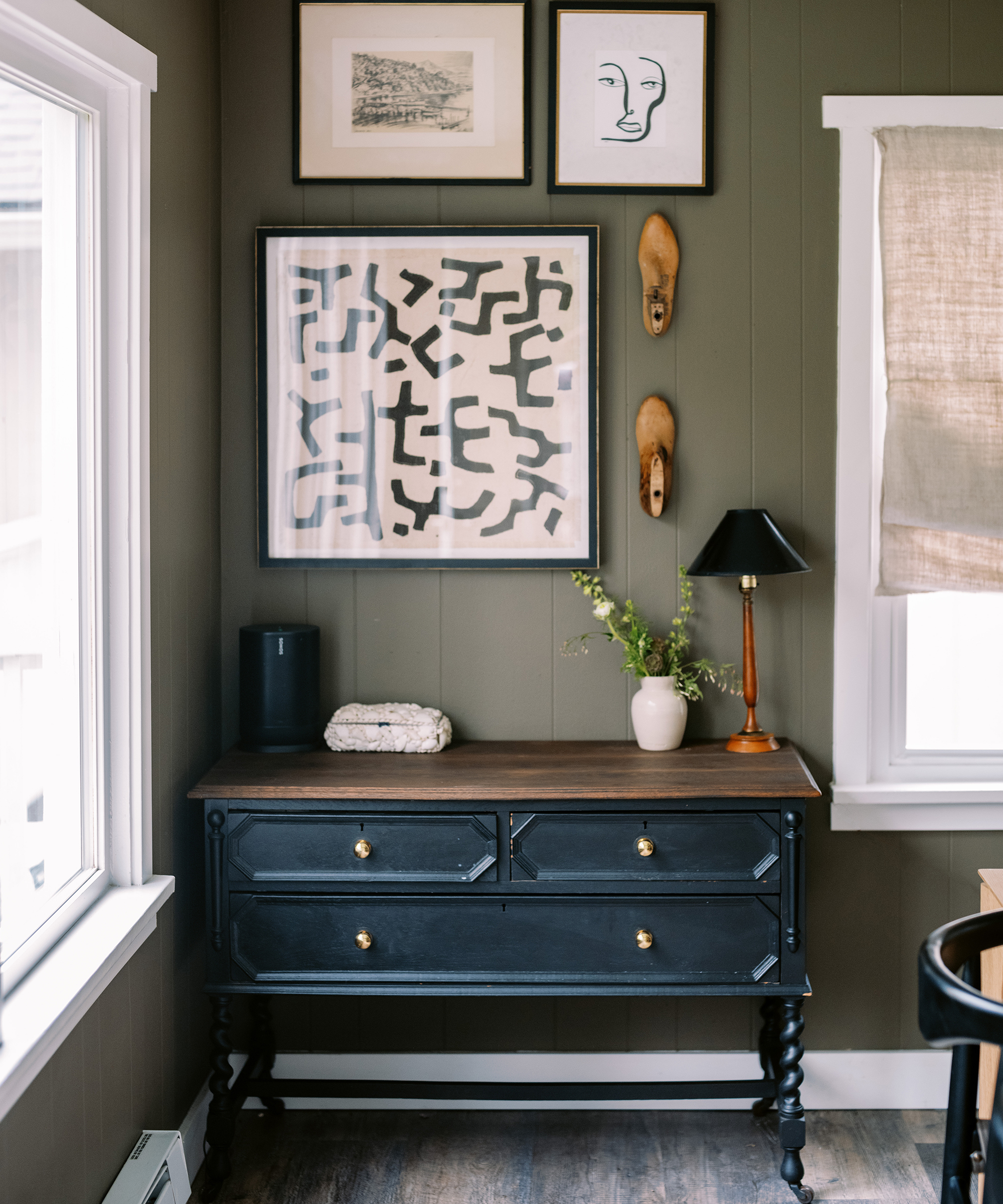 Kennesha Poe-Buycks of Restoration House's dining room with a blue credenza and three painting hung above it.