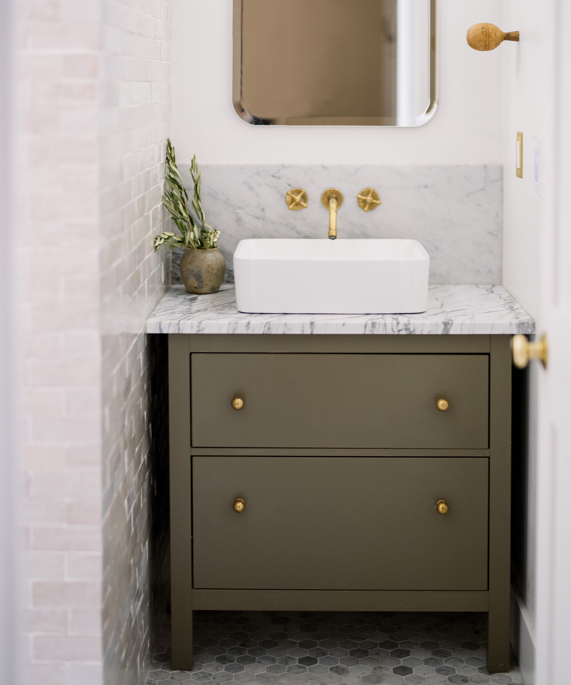 Kennesha Poe-Buycks of Restoration House's bathroom with olive-colored vanity and marble sink.