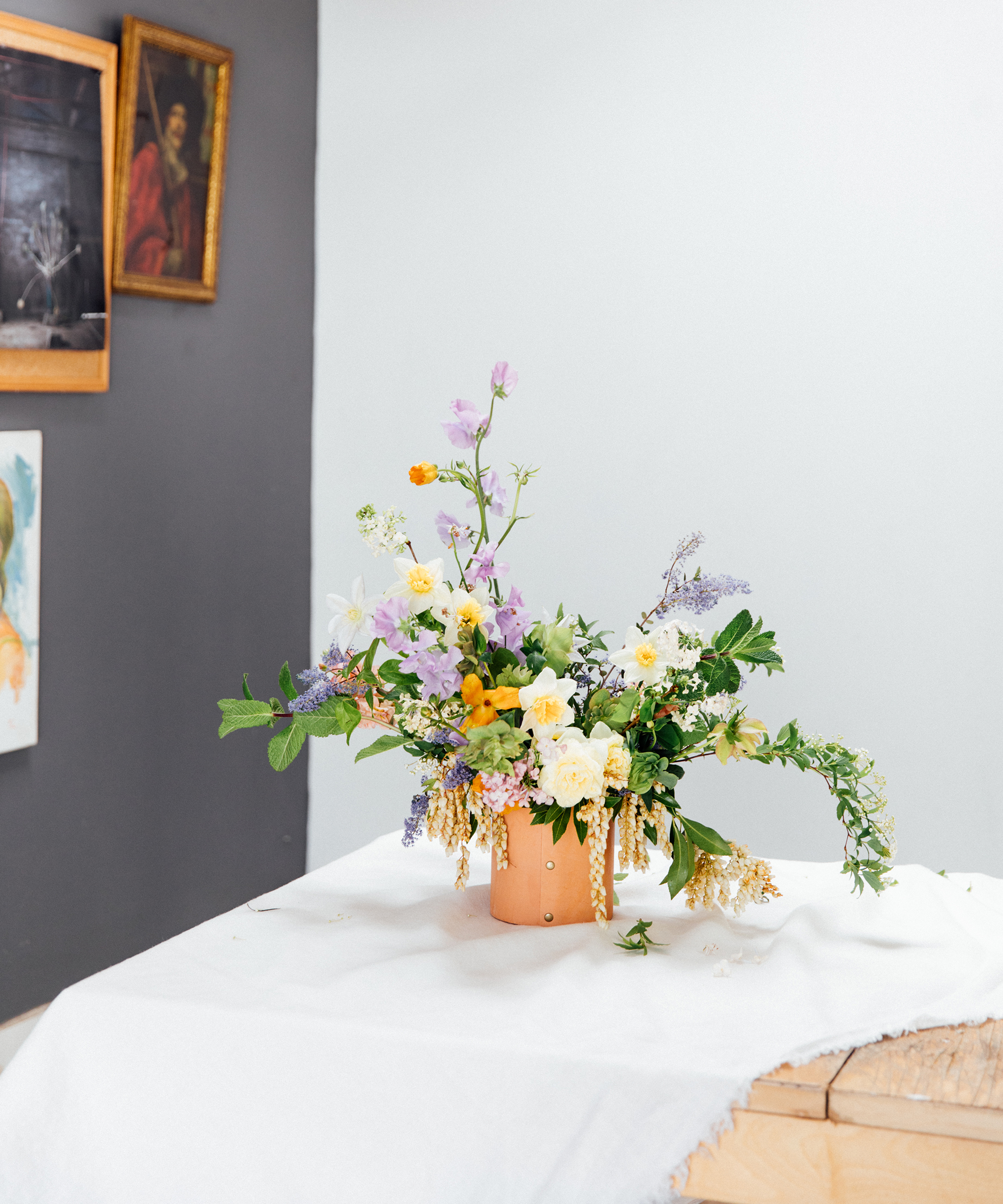 Pigsty spring floral arrangement in a Jenni Kayne leather rivet vase with an assortment of flowers.