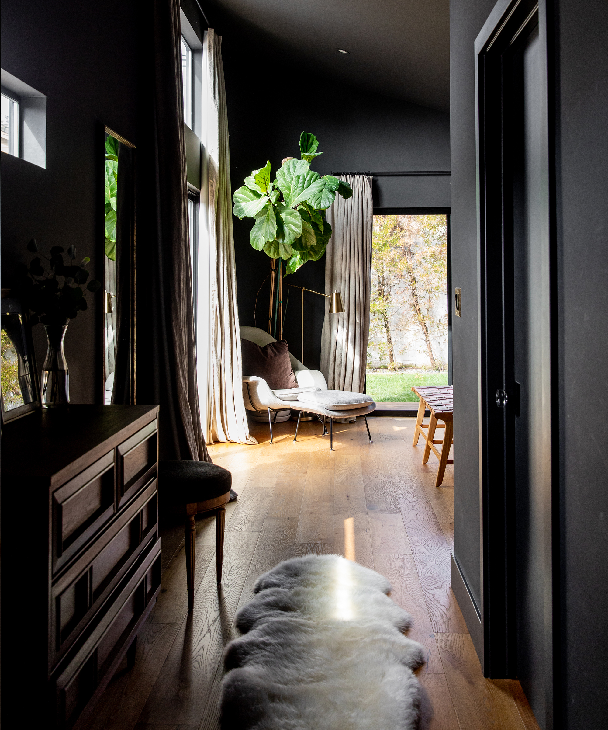 The hallway of Alex Taylor's home leading to her bedroom with a jenni kayne sheepskin on the ground and a plant in the background.