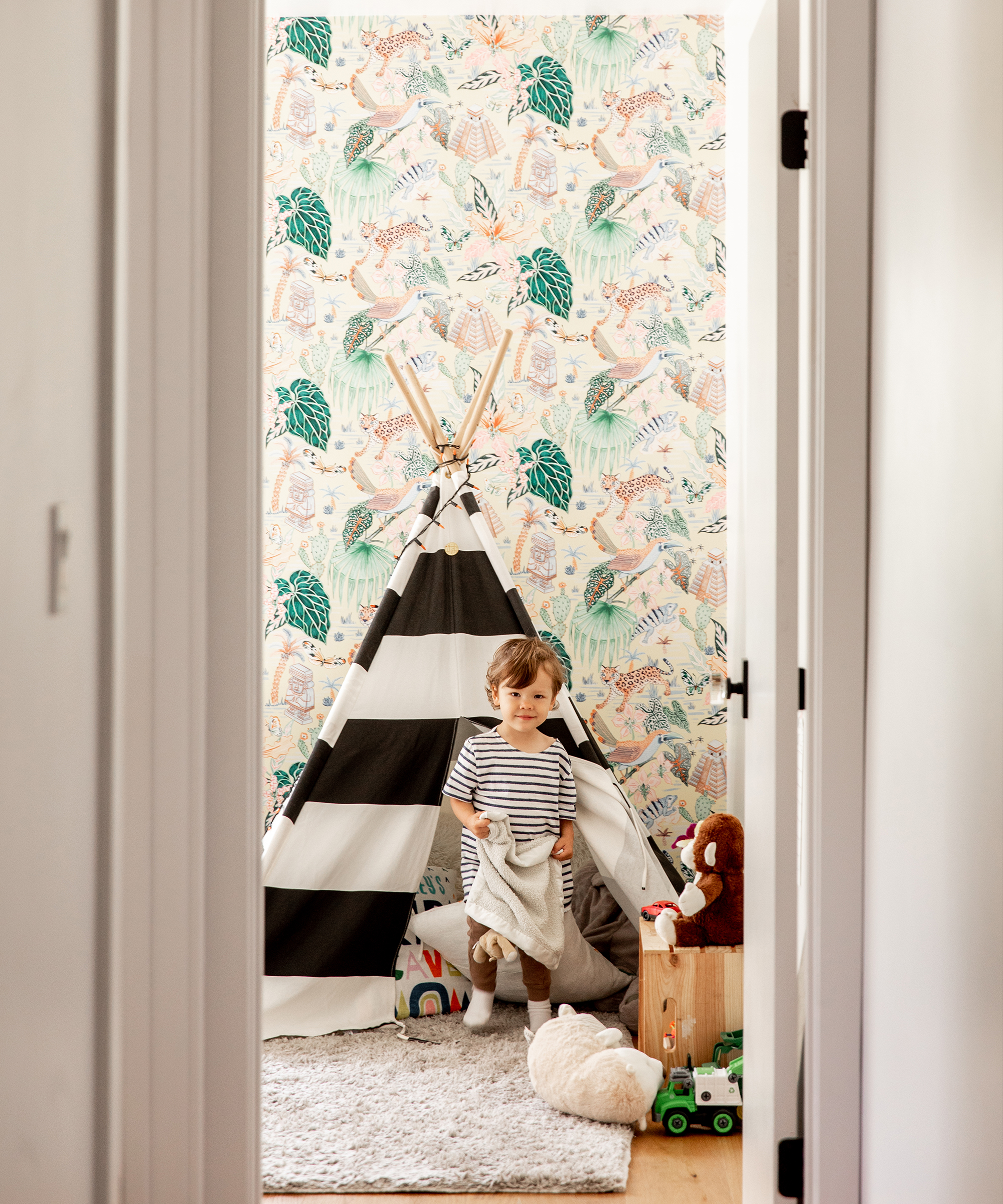 Alex Taylor's young son in the doorway of his room inside his play tent holding his blanket and wearing saint james x jenni kayne.