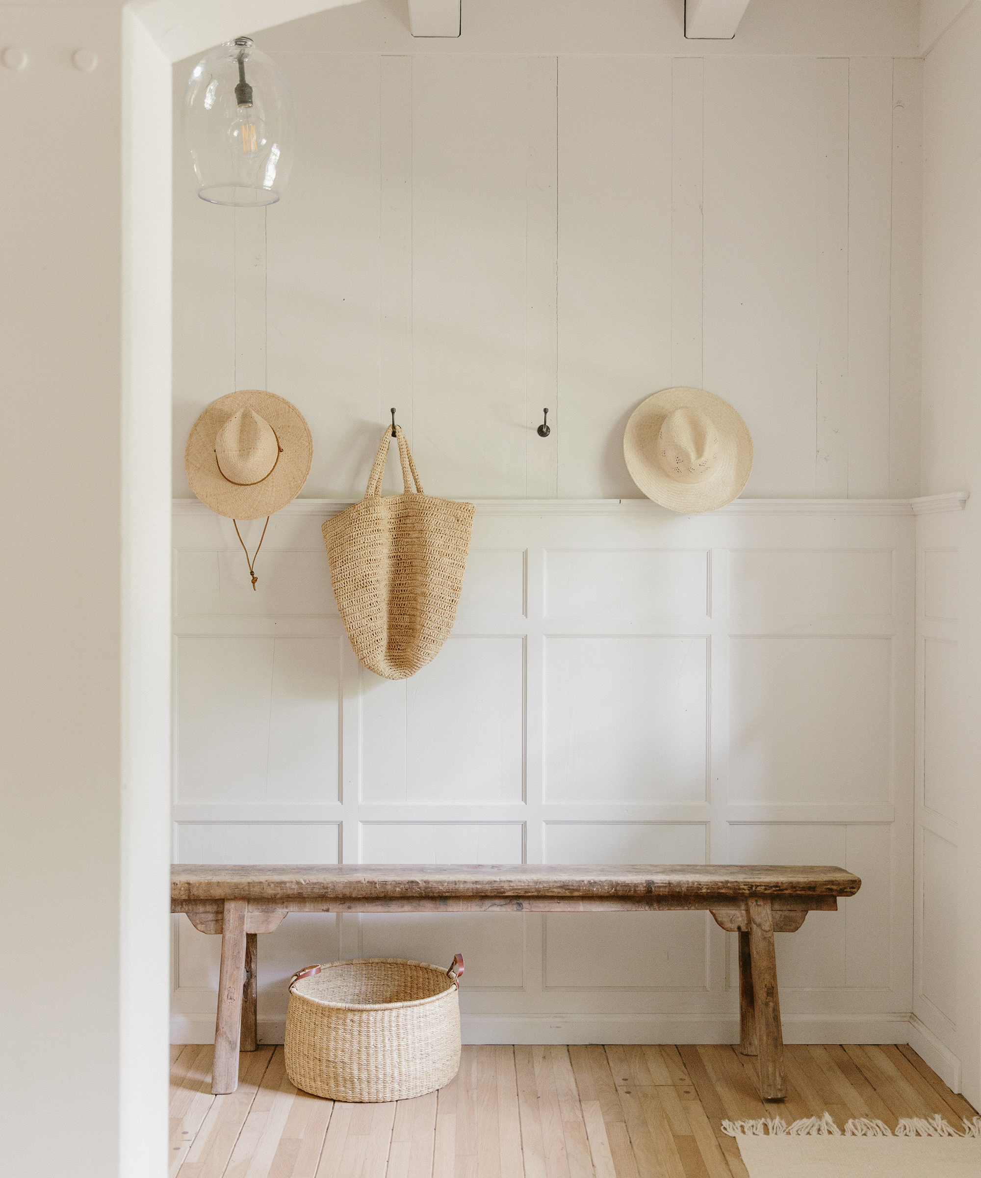 Julia Hunter's entryway with a bench, hooks with hats and bags on it, and a rug,