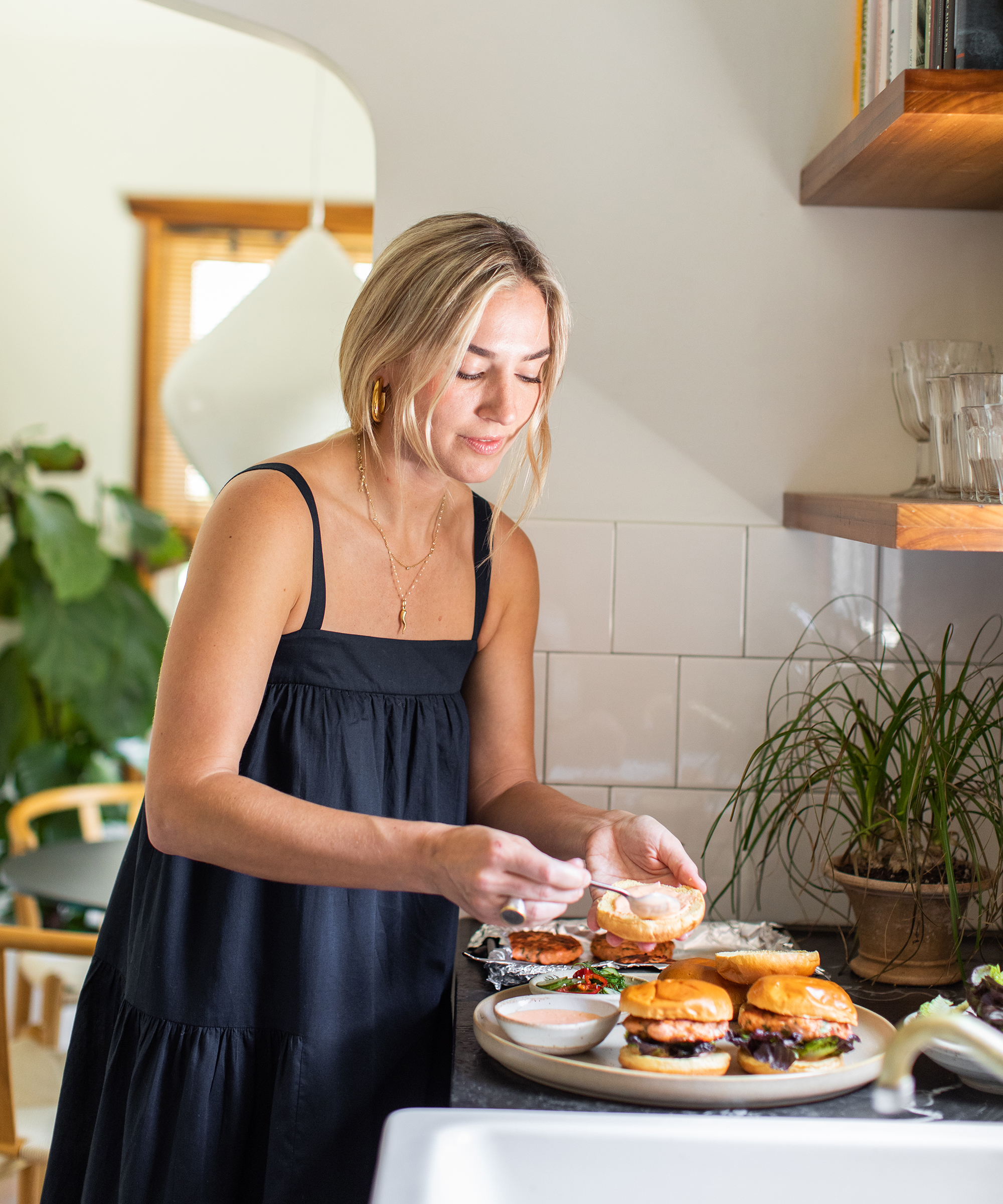 Olivia Muniak of La Cura in her kitchen plating salmon burgers onto a platter.
