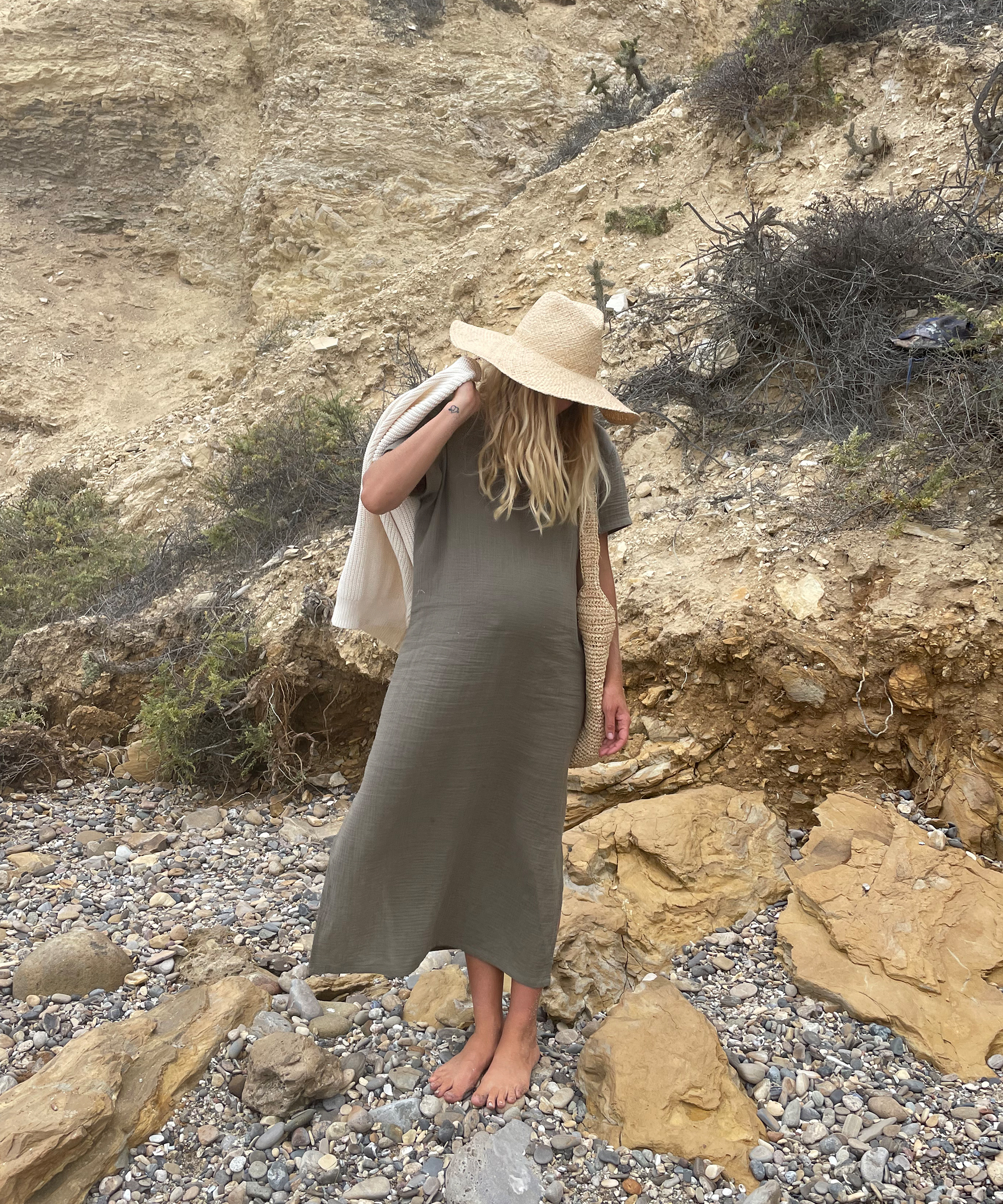 Leah Bradley on the beach wearing jenni kayne caftan dress, safari hat, and cotton cocoon sweater.