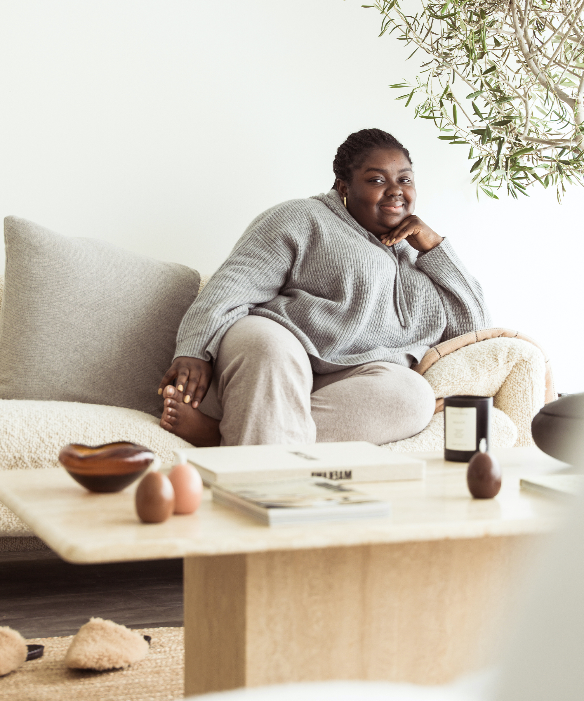 Abisola Omole sitting on the sofa in her London N1 Studio wearing jenni kayne cashmere fisherman hoodie.