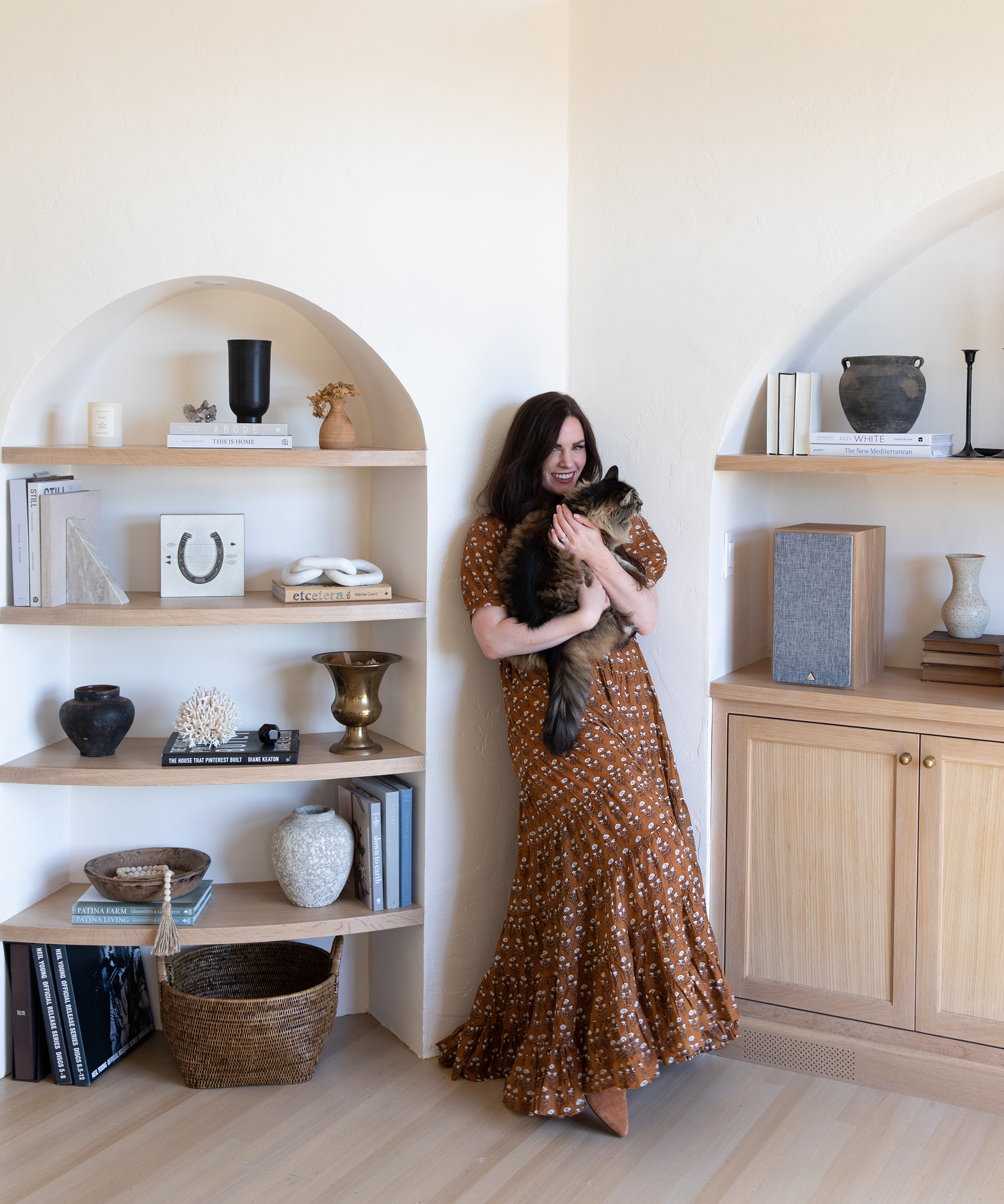 Image of Brodie Jenkins standing in front of her bookshelf holding her cat.