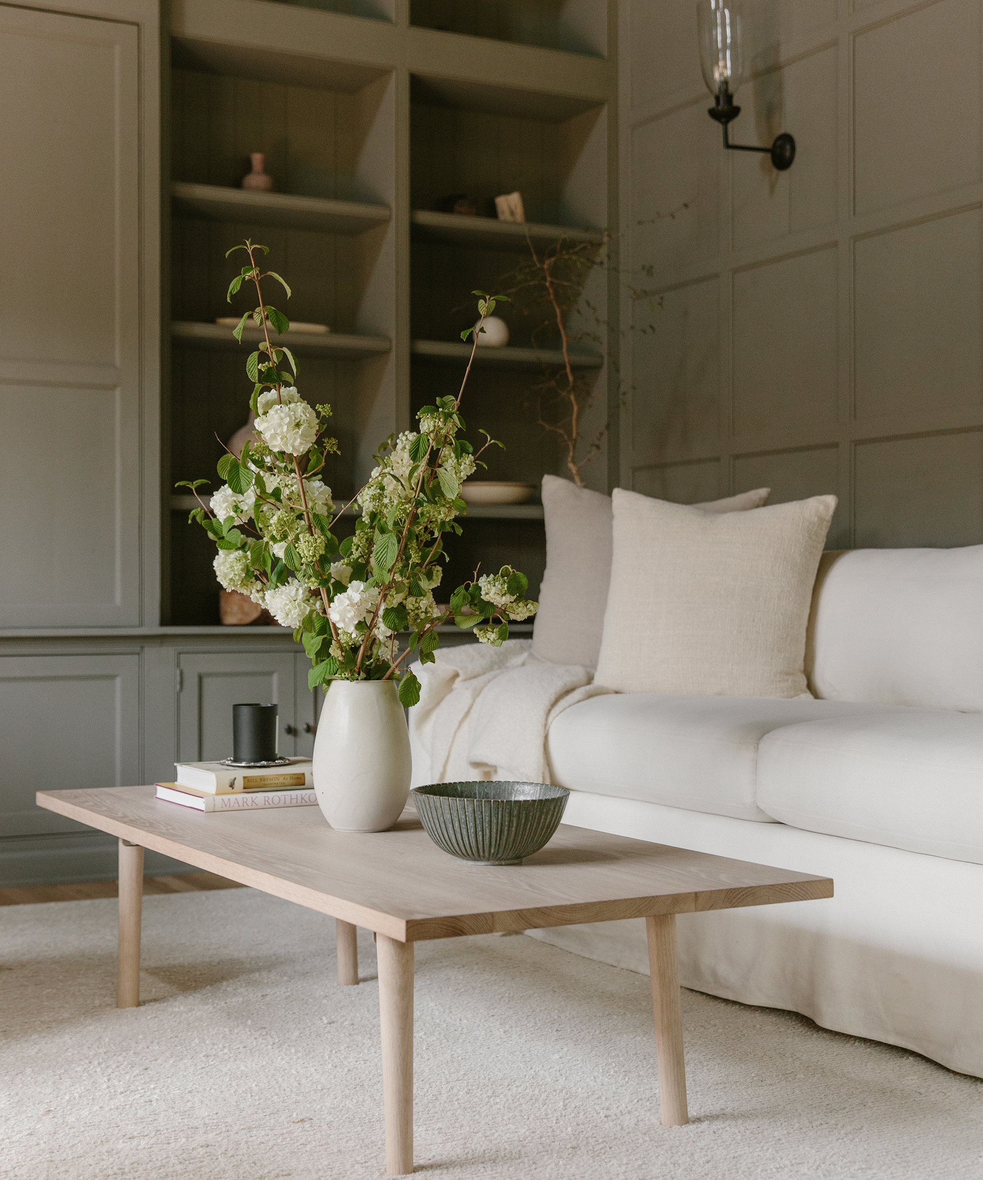 An after shot of Julia Hunter's Mandeville Canyon den with harbor sofa, canyon coffee table, and a vase of flowers.