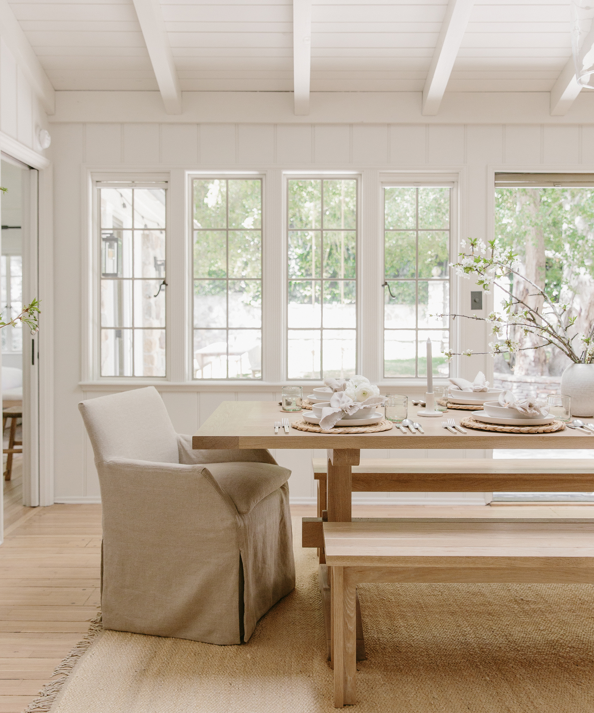 Julia Hunter's living room with jenni kayne dinning table and bench on top of farmhouse rug set with ceramic dinnerware.