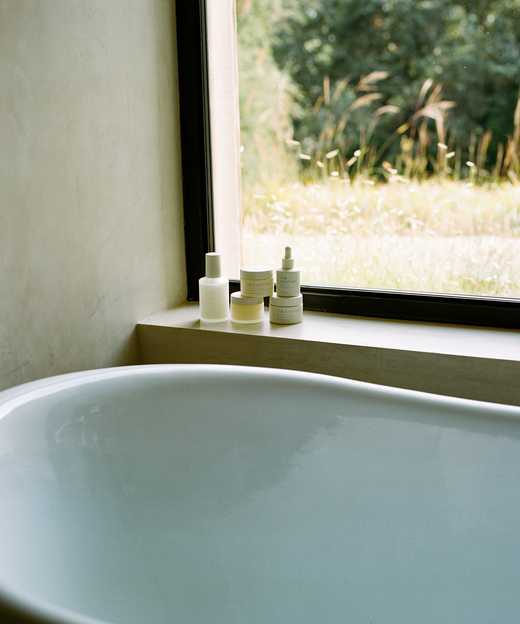 Oak essentials five products sitting on the edge of a window over a bathtub.