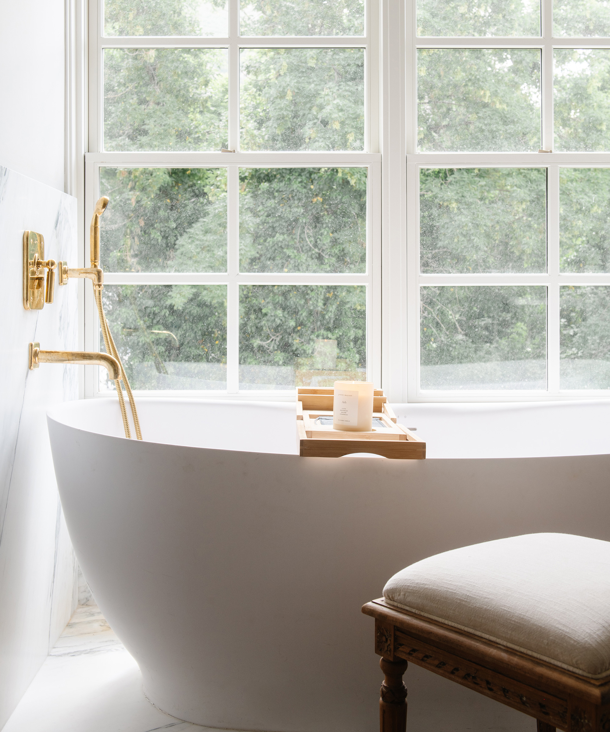 Marianne Brown's bathroom with bathtub and gold fixtures next to a window.