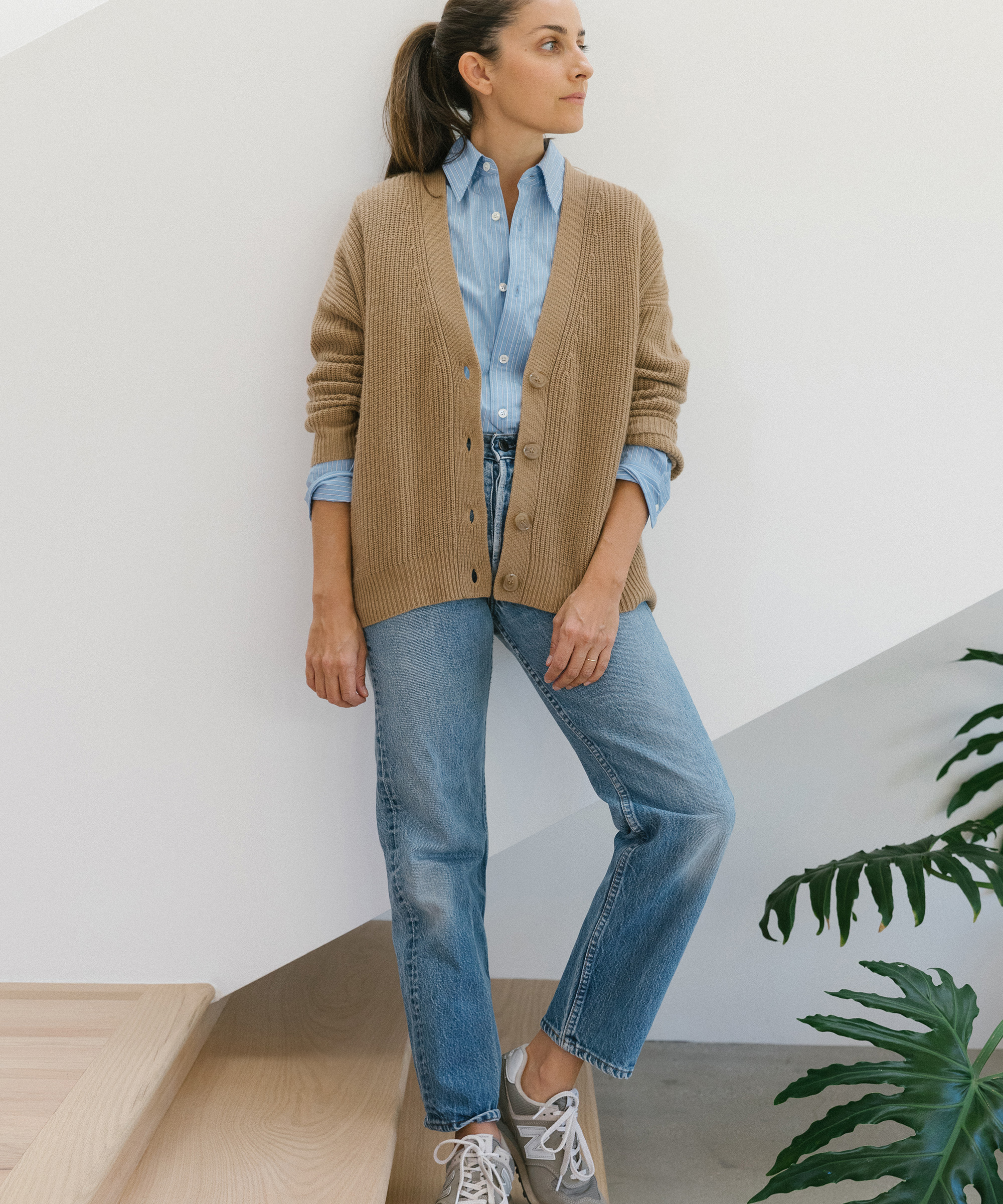 model wearing cropped cardigan in camel with button-up shirt tucked in underneath and new balance sneakers.