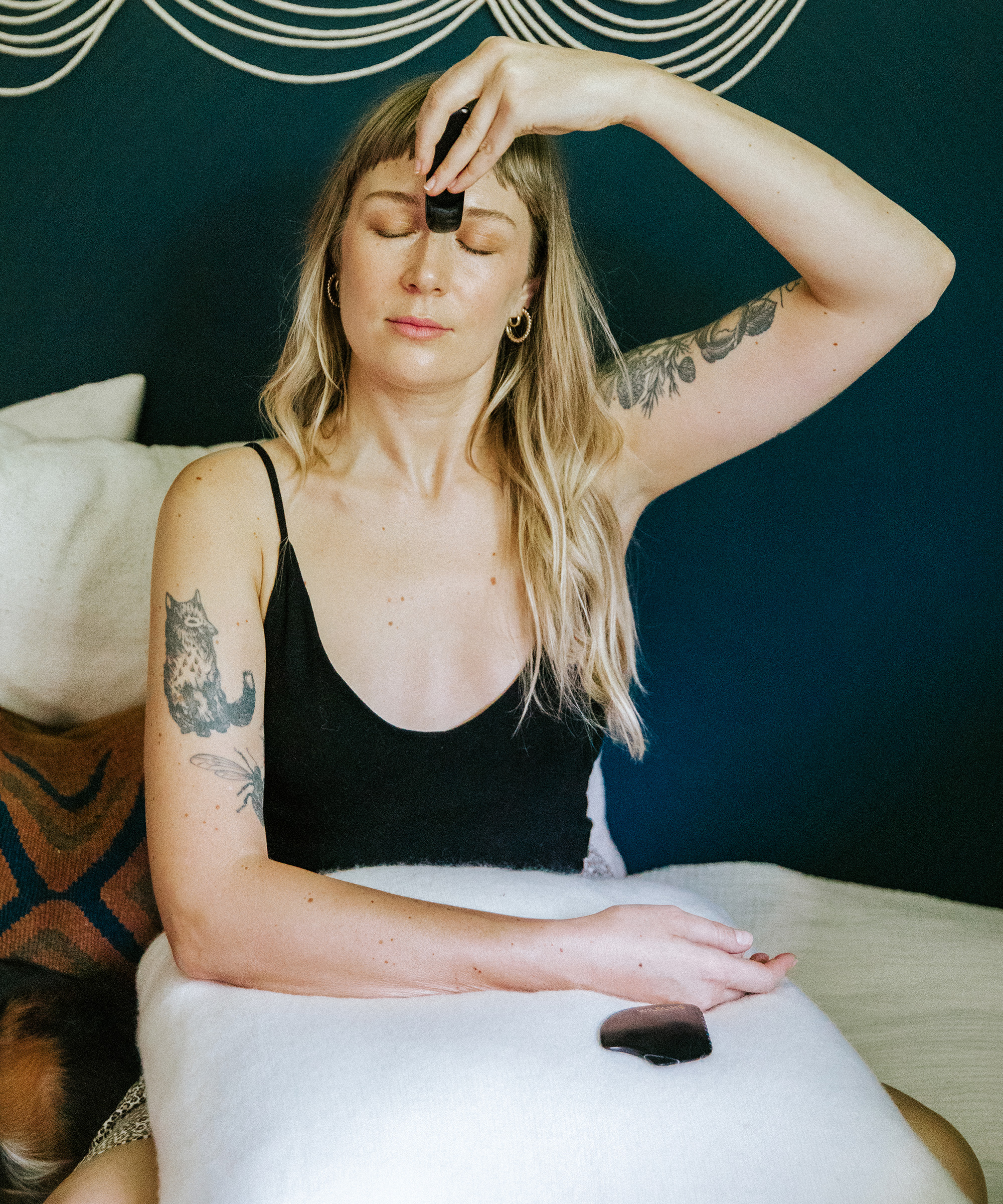 britta plug sitting in her living room using her gua sha stone.