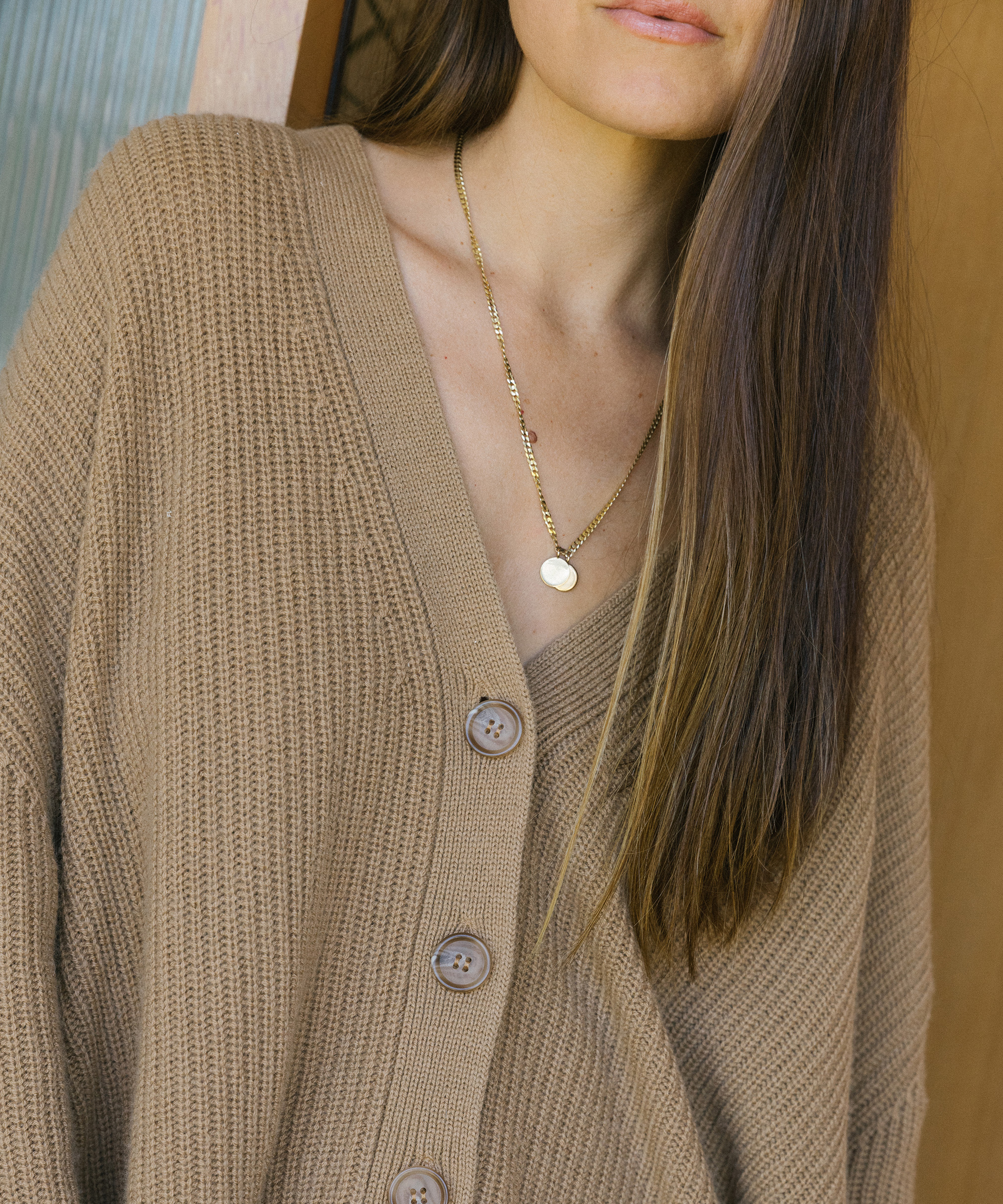 model wearing cropped cocoon cardigan in camel with necklaces on.