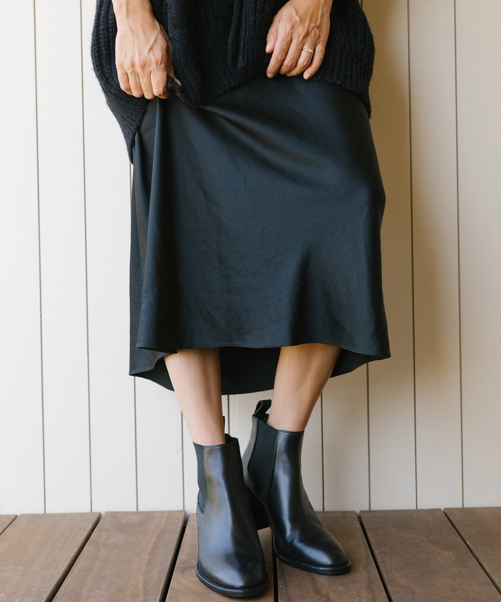 model wearing jenni kayne cable cocoon cardigan in black with black heeled chelsea boots.