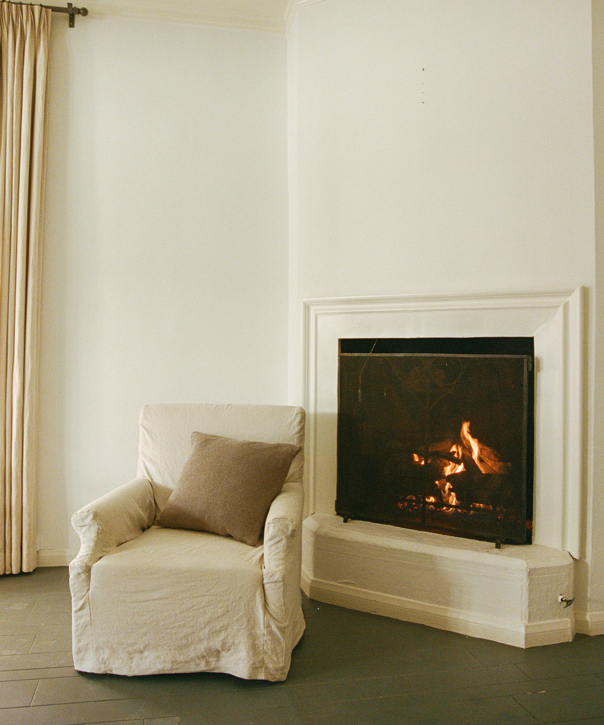 image of jake arnold's apartment bedroom with a white chair next to a fireplace