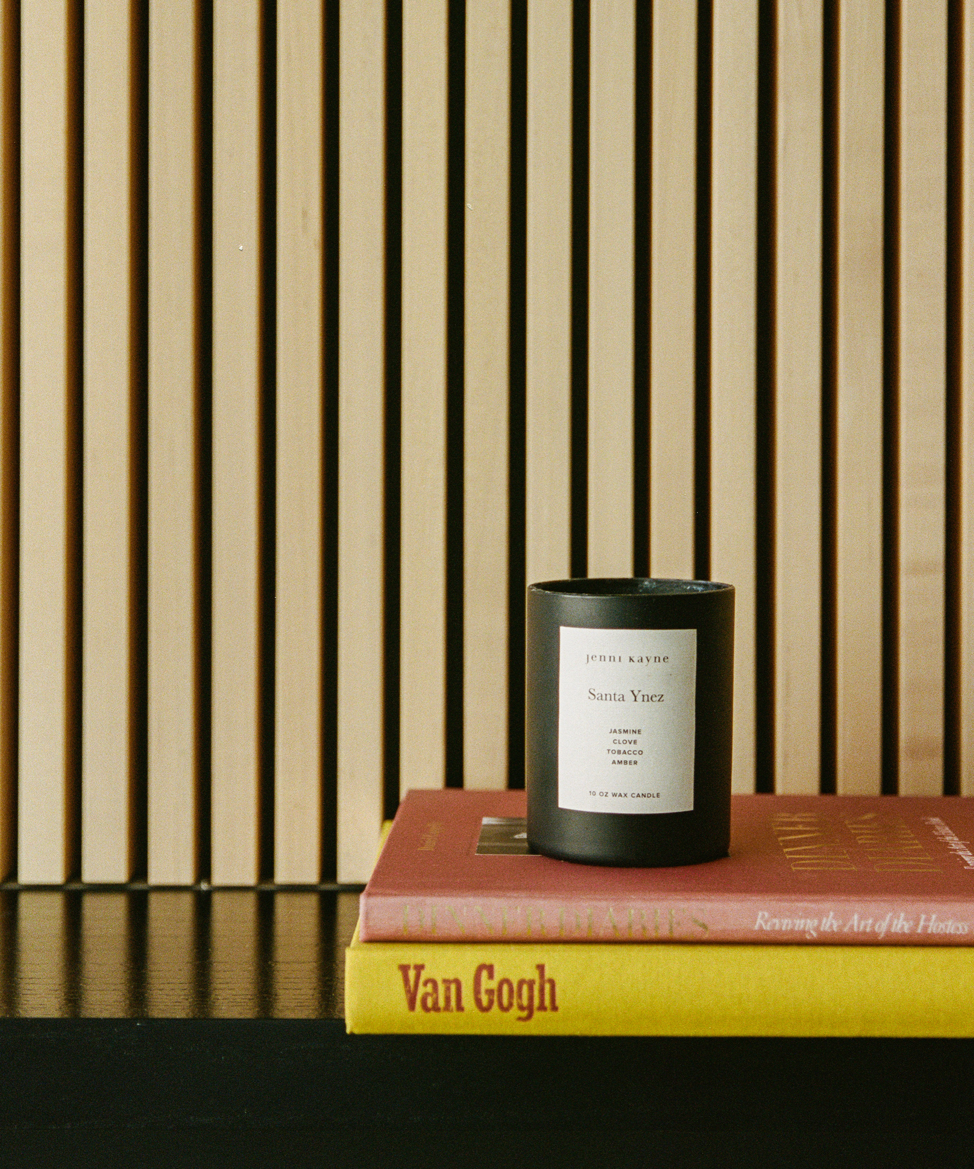 A candle on top of books creates a cozy ambiance, echoing the serene style of Elisa Baran.