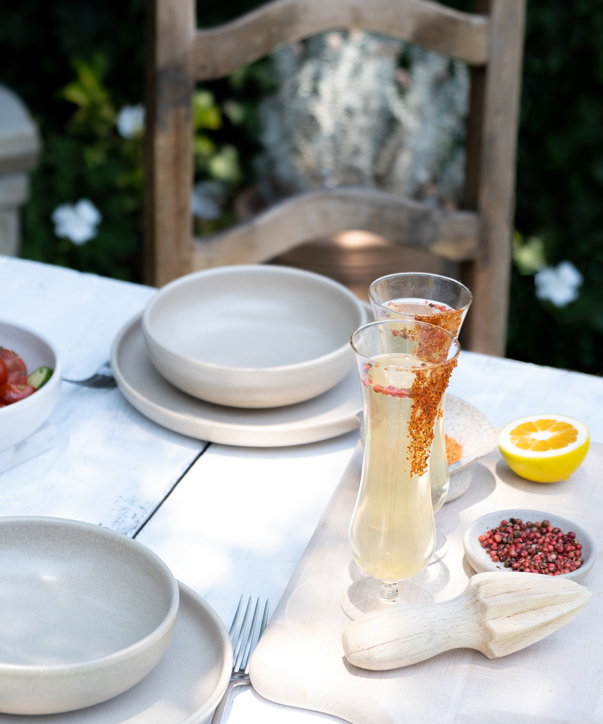 Two tall glasses of a light-colored drink with spiced rims sit on a white outdoor table, surrounded by neutral plates and fresh decor, offering refreshing inspiration for your next room renovation.