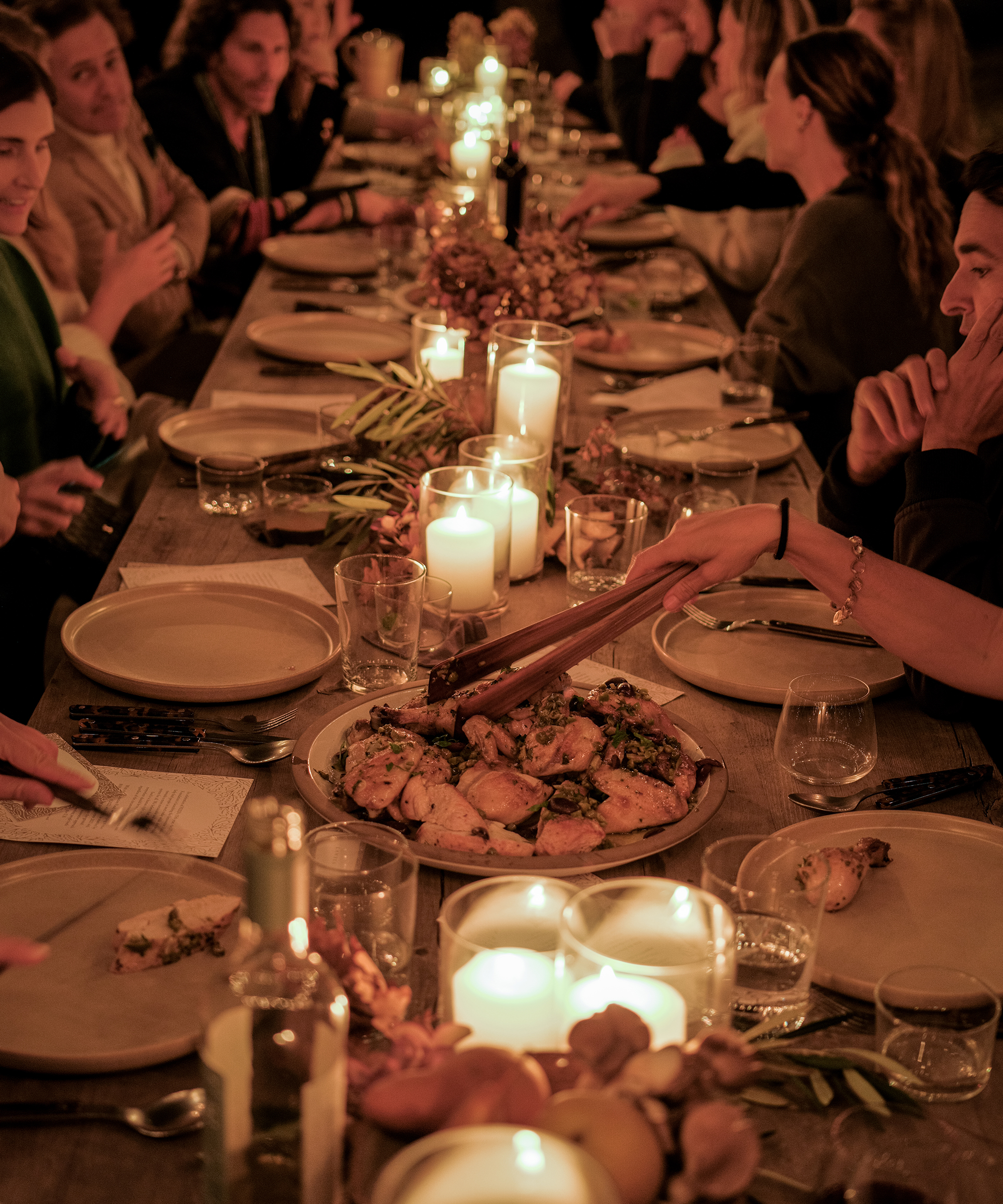 jenni kayne candlelight dinner table outdoors with guests chatting and serving themselves entrees