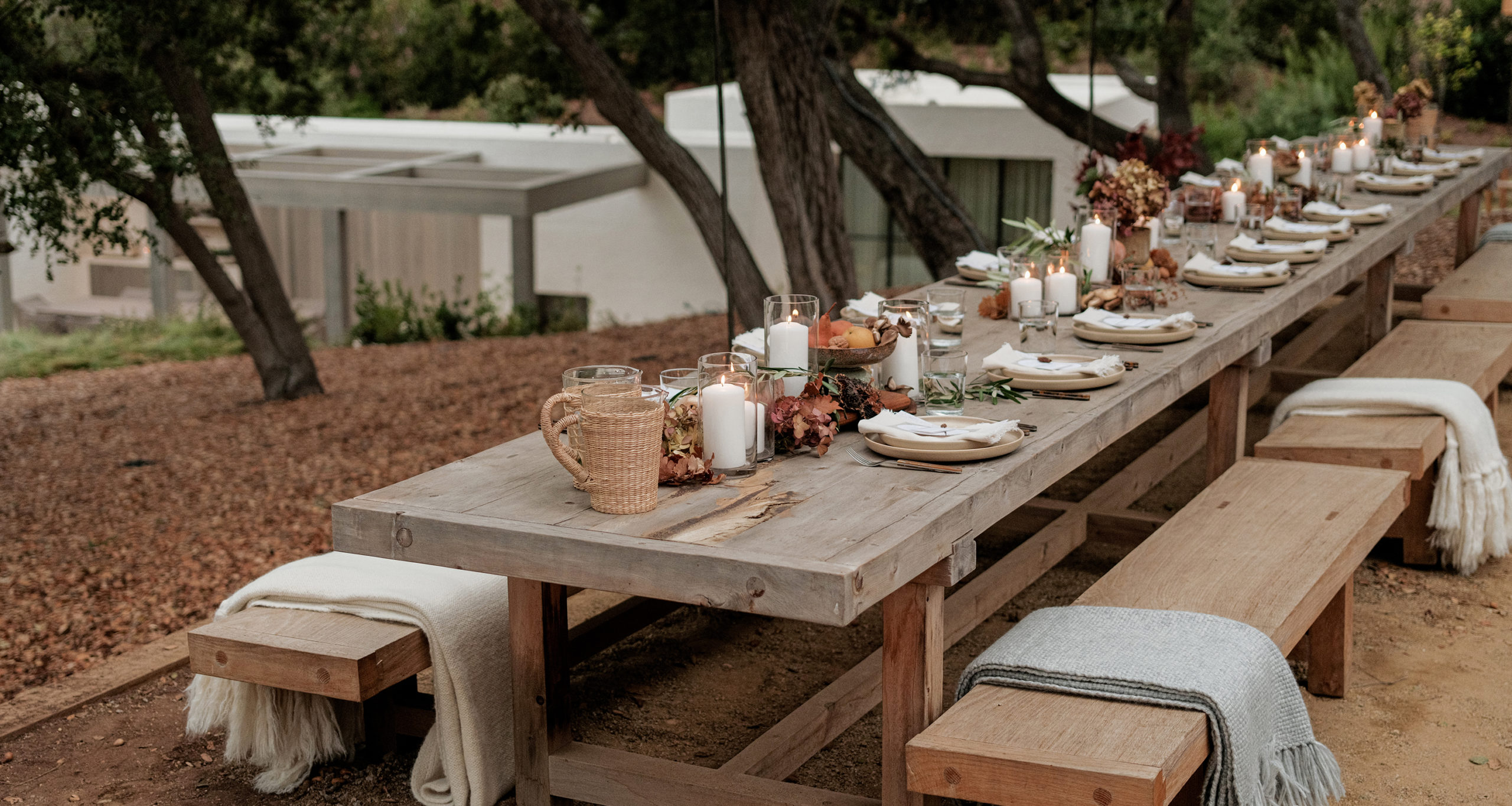 feed-supper-jenni-kayne-home-wide-shot-full-outdoor-table-facing-house-and-trees-seagrass-pitchers