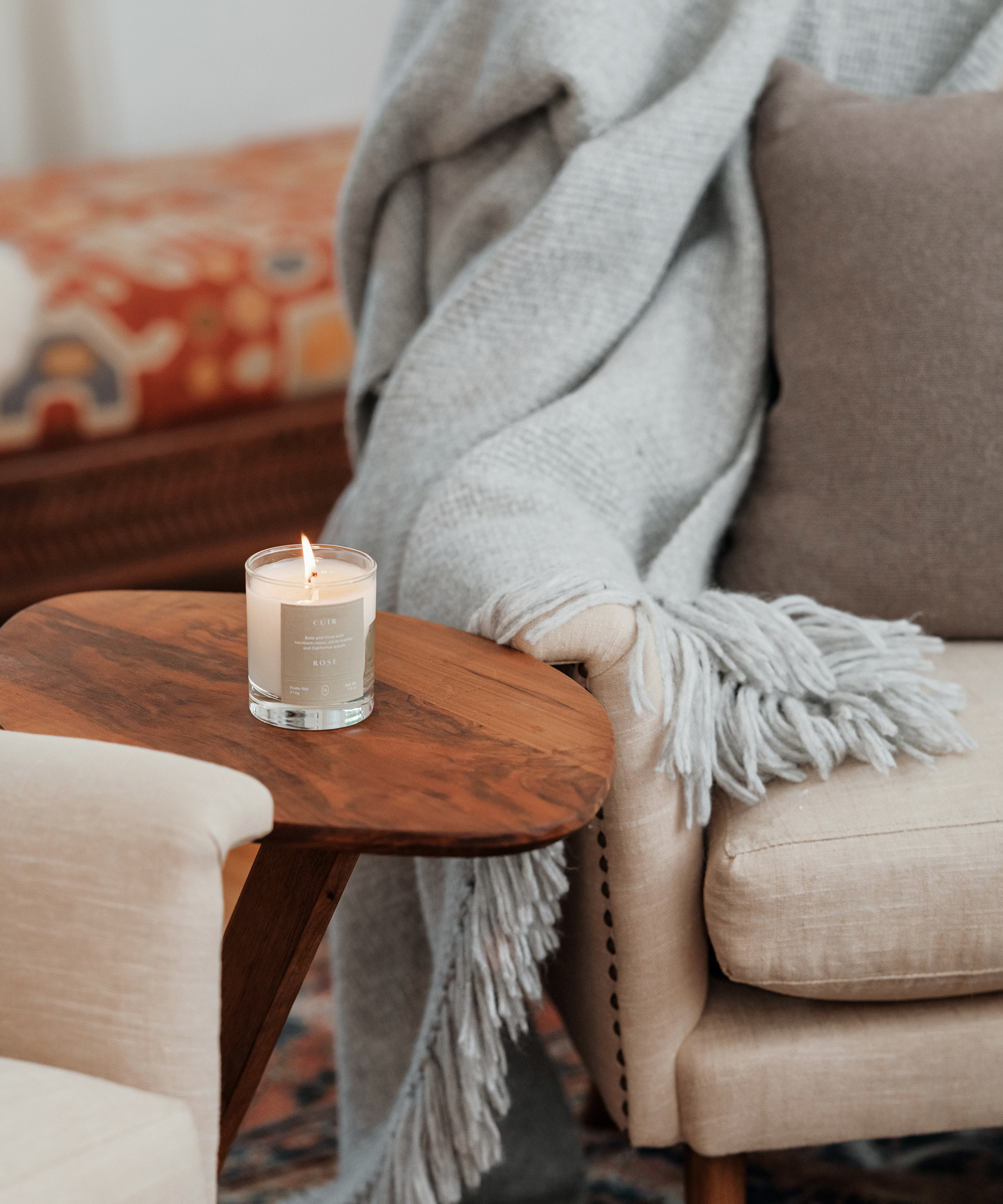 jenni kayne candle burning on wood side table